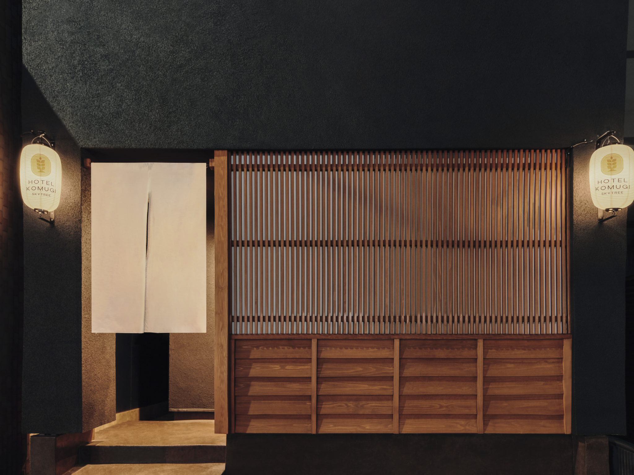 Top-down view of a Japanese-themed entrance with two lanterns on the side, a white fabric curtain, and a wooden lattice wall.