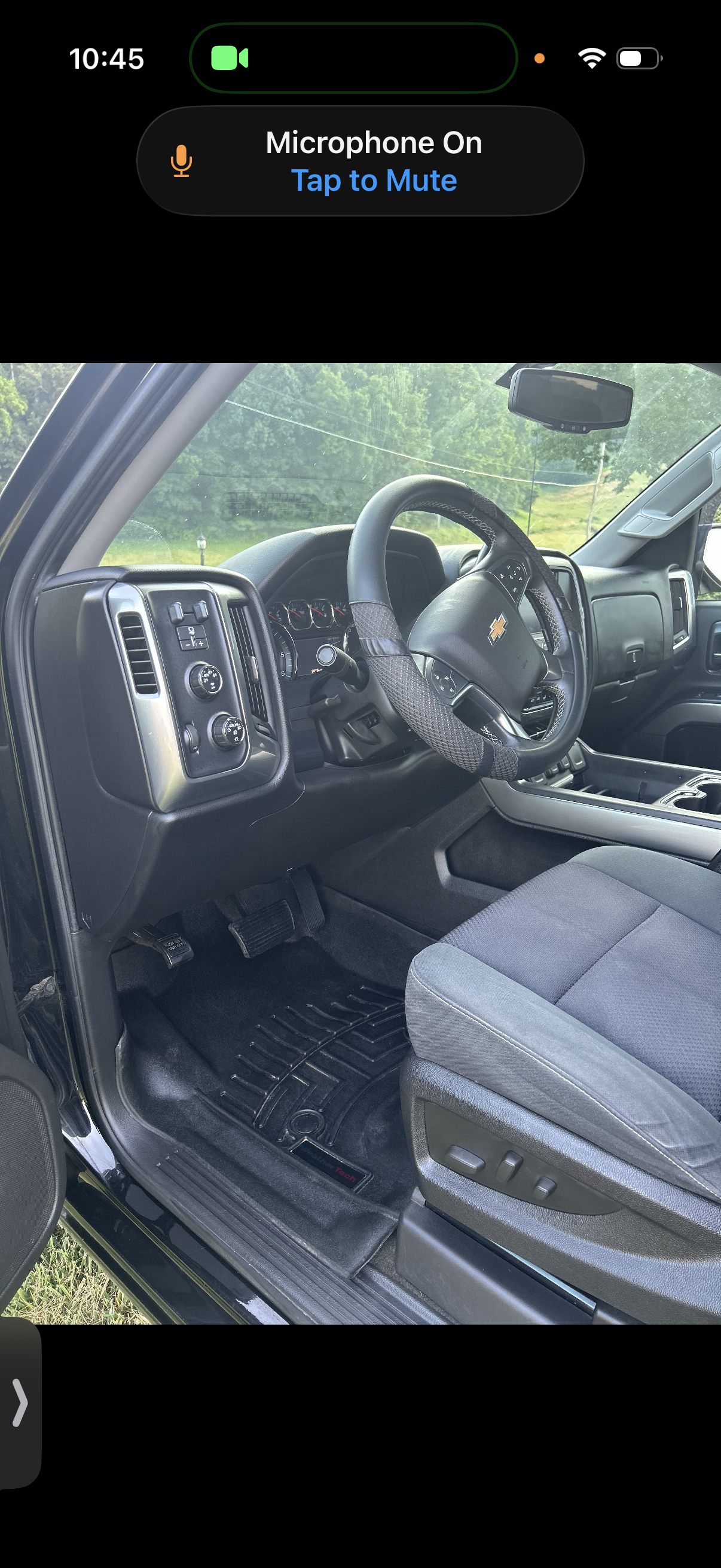 Interior of a Chevrolet truck showing the driver's seat, steering wheel, dashboard, and part of the door with window controls.