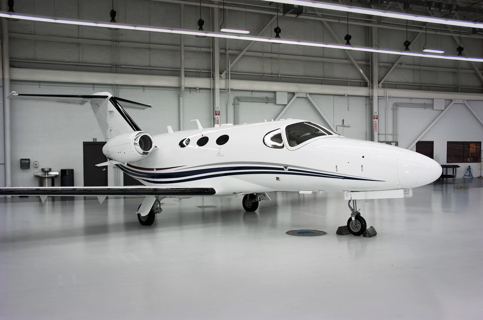 A white private jet inside an airplane hangar.