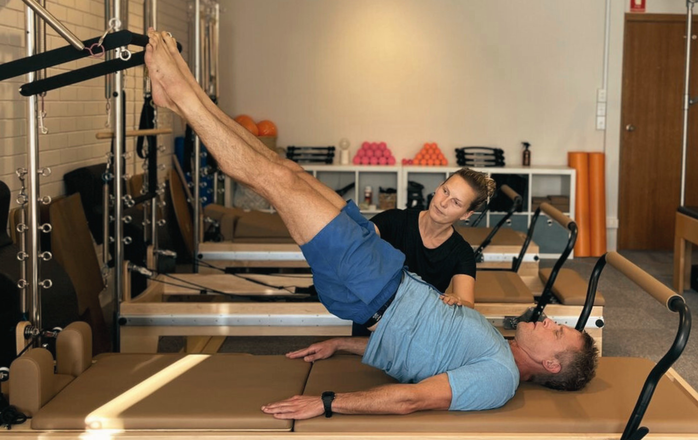maja loekkegaard assisting athlete with the Pilates Shoulder Briddge performed on the Tower