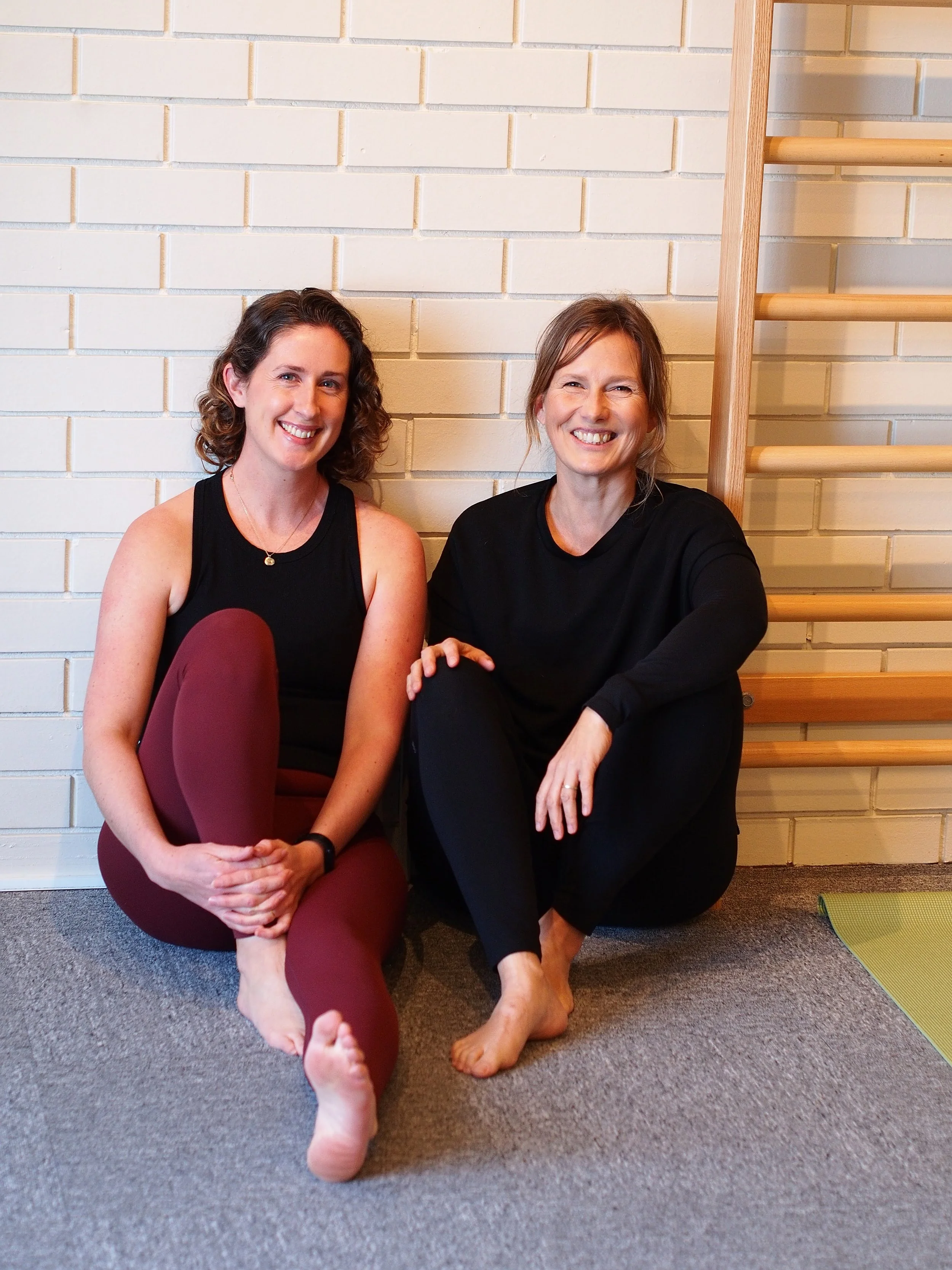 Pilates Practitioner Maja Loekkegaard and Women's Health Strength & Conditioning coach Zoe Wood sitting against ladder in Movemenv Lab Phillip Island