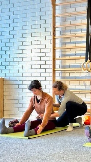 Hands-on cueing with the Pilates Matwork repertoire exercise called the Spine Stretch exercise  