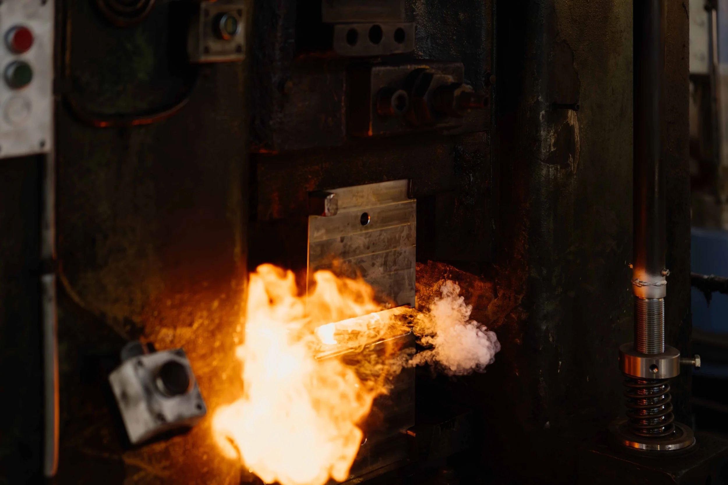A metal workshop scene with sparks and flames from a metal being cut or welded.