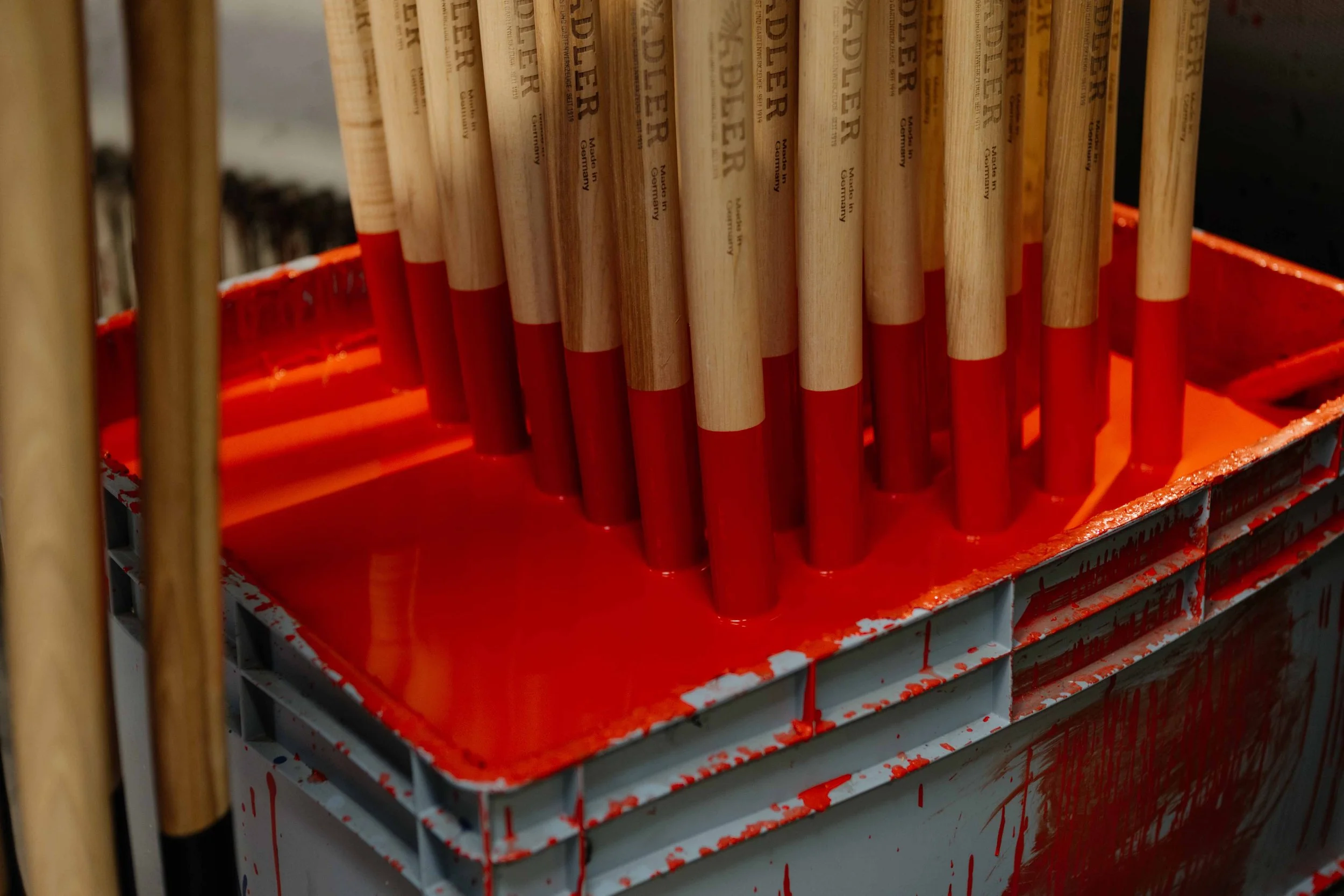 Painted wooden stilts stored in a bright red paint tray.