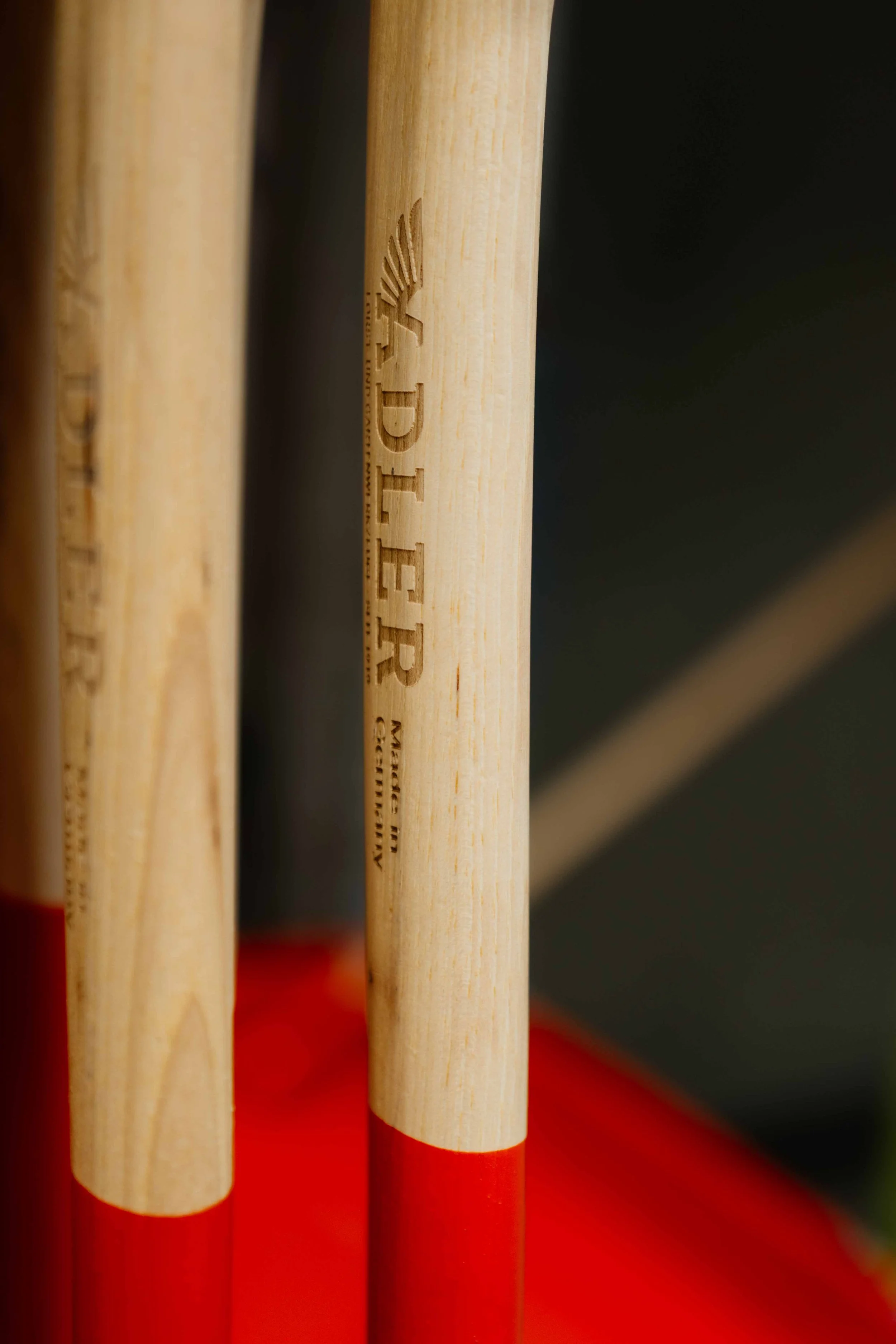 Close-up of wooden gardening tools with red painted tips, showing the brand 'DLEER' on one handle.