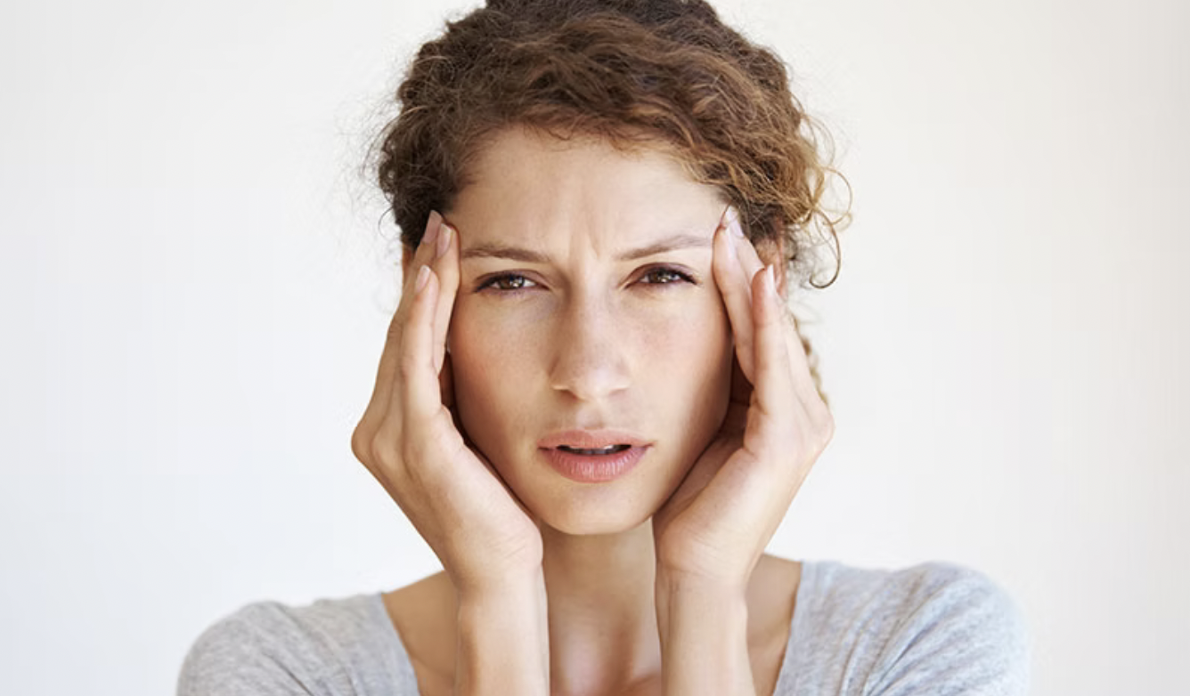 A woman holding her head with both hands, looking confused or stressed.