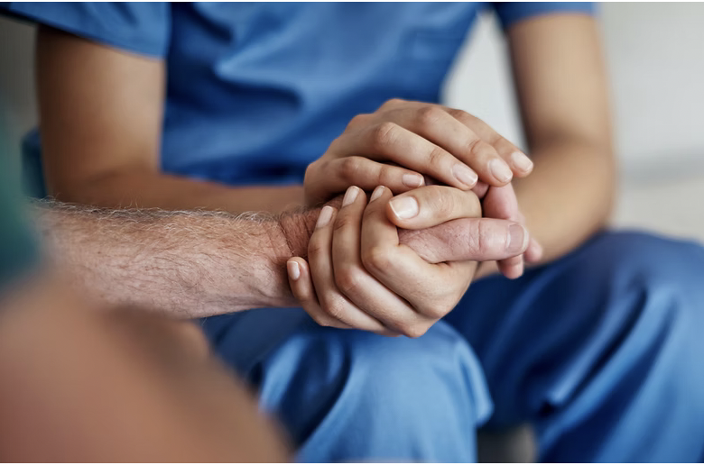 Close-up of a healthcare professional holding a patient's hand during a consultation.