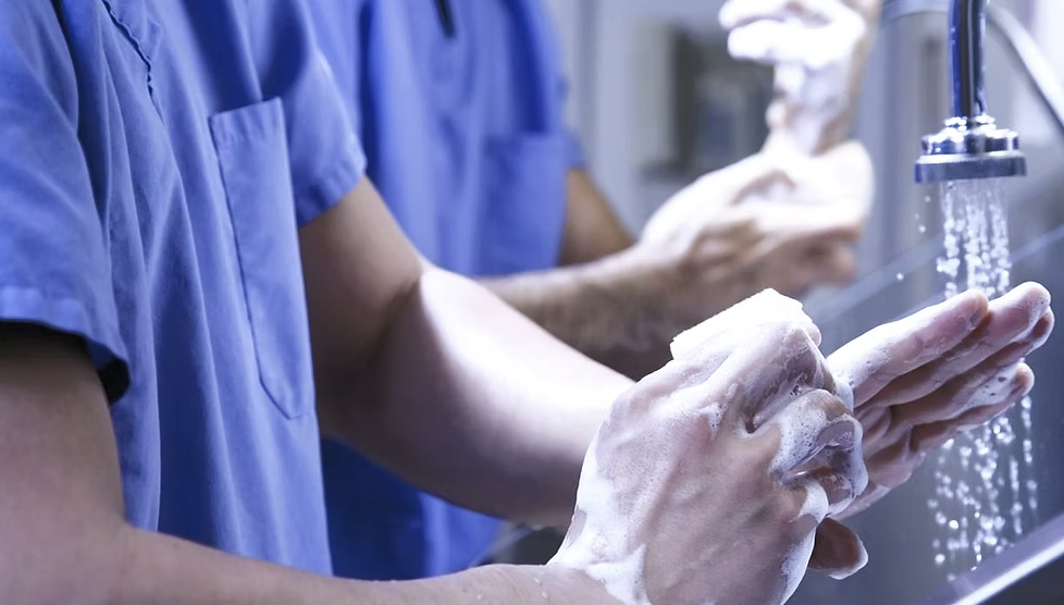 People washing hands in a sink at a water faucet, with soap lather.