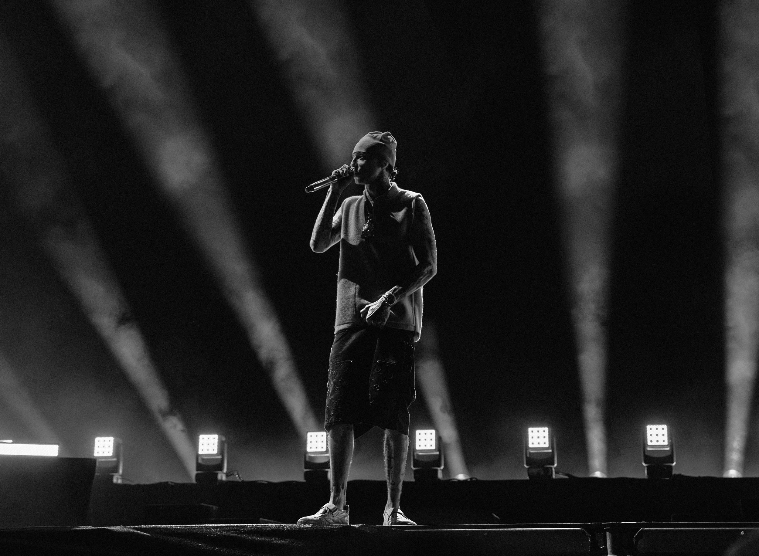 A female singer performing on stage with spotlights shining behind her, in black and white.