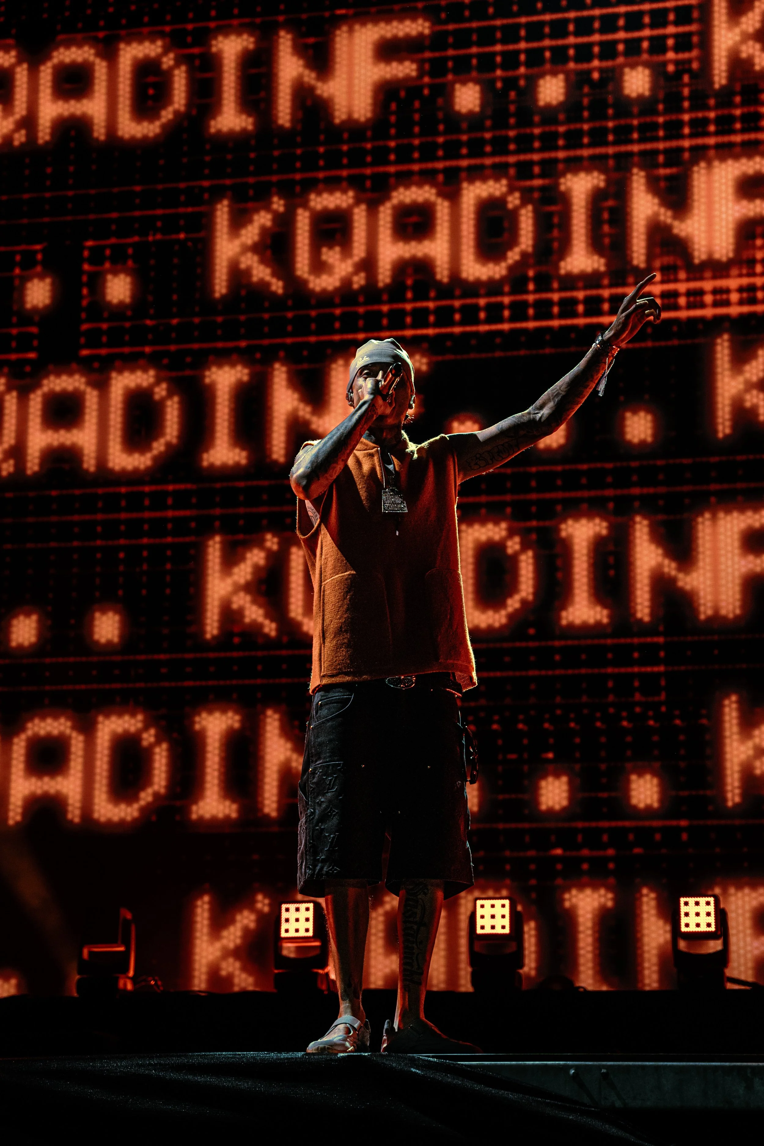 A rapper performs on stage with a large digital screen displaying repeated 'KODAK' text in the background.