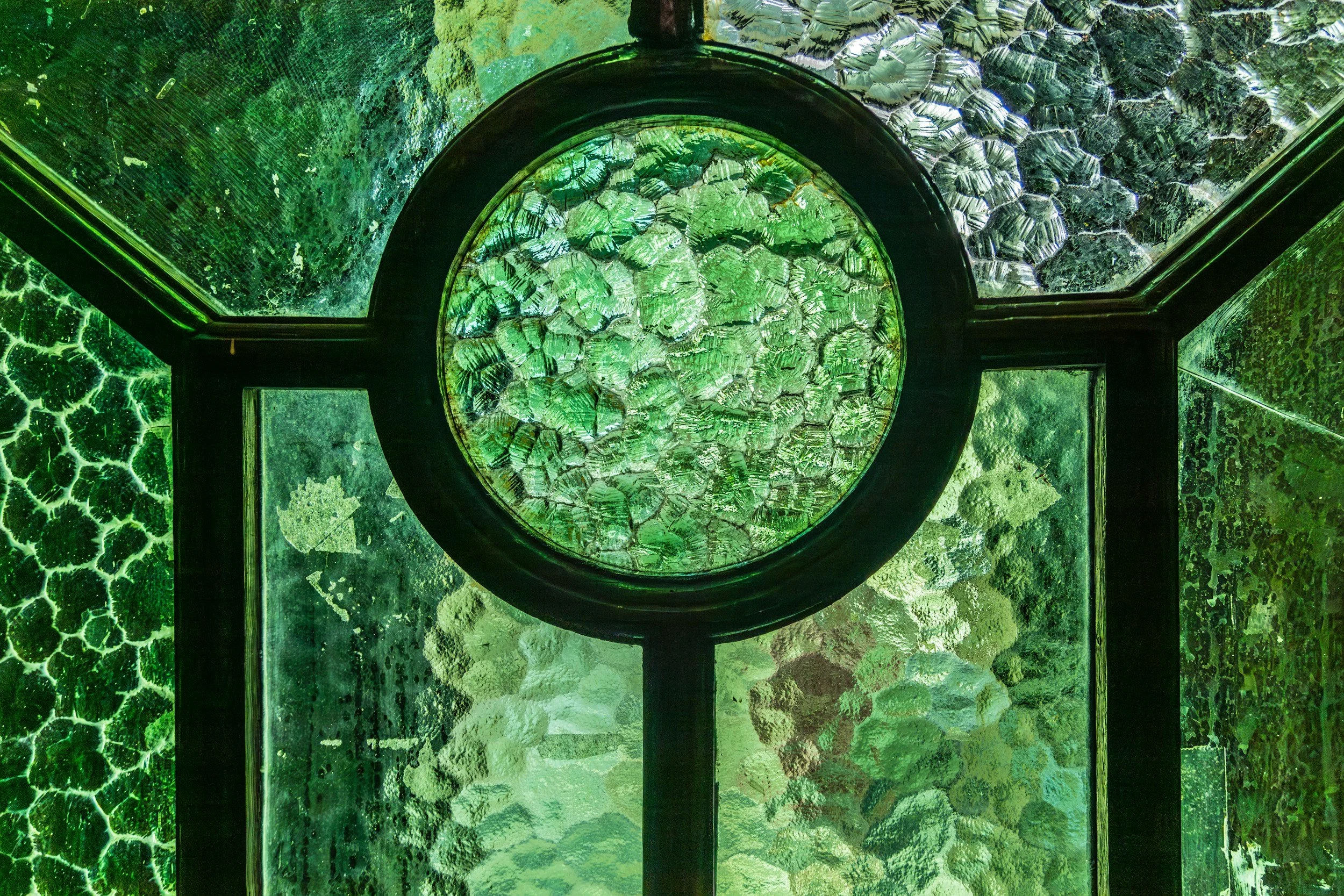 Close-up view of stained glass windows with various shades of green and textured glass.