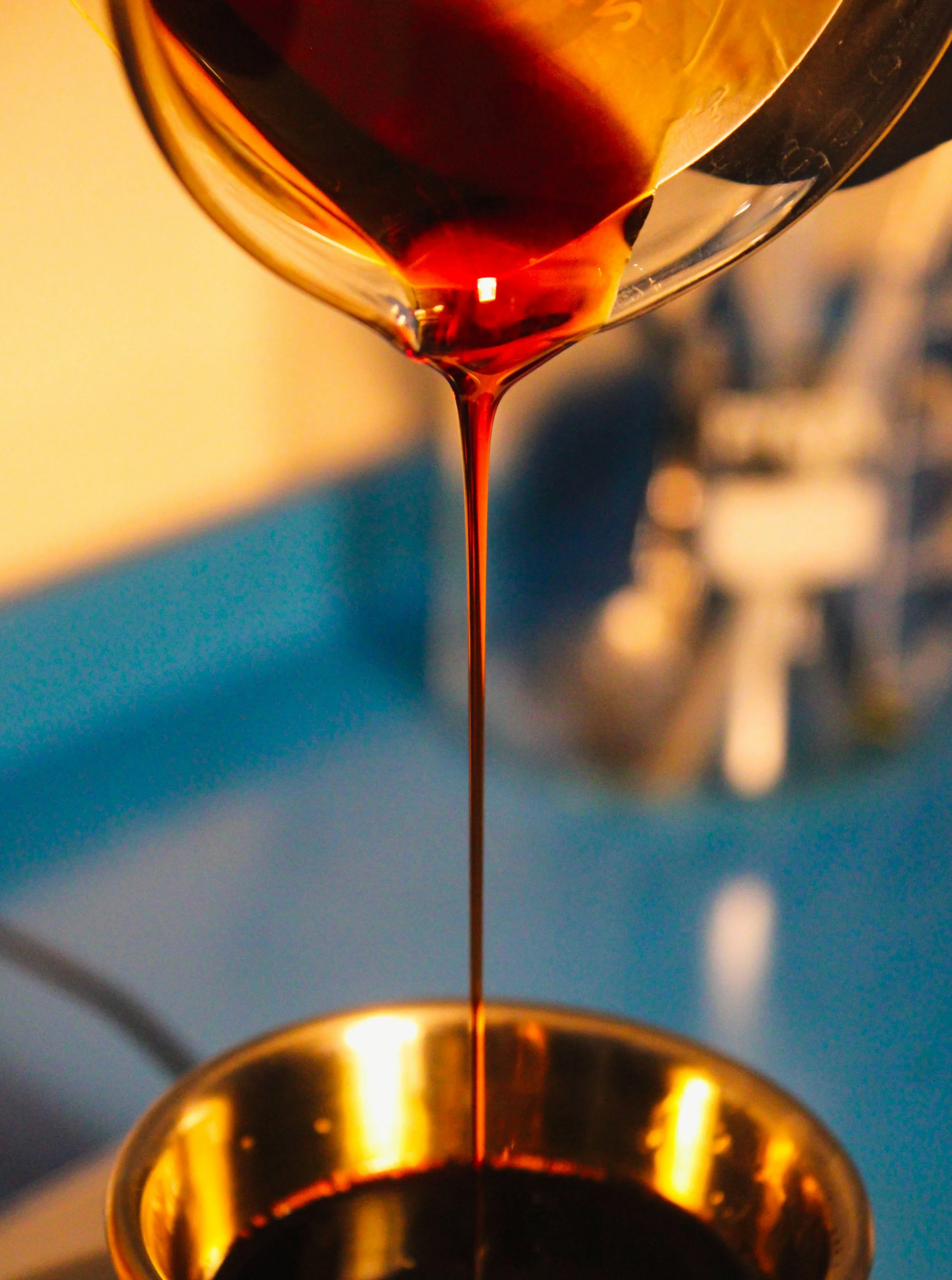 Close-up of red wine being poured from a glass into a gold-rimmed wine glass.