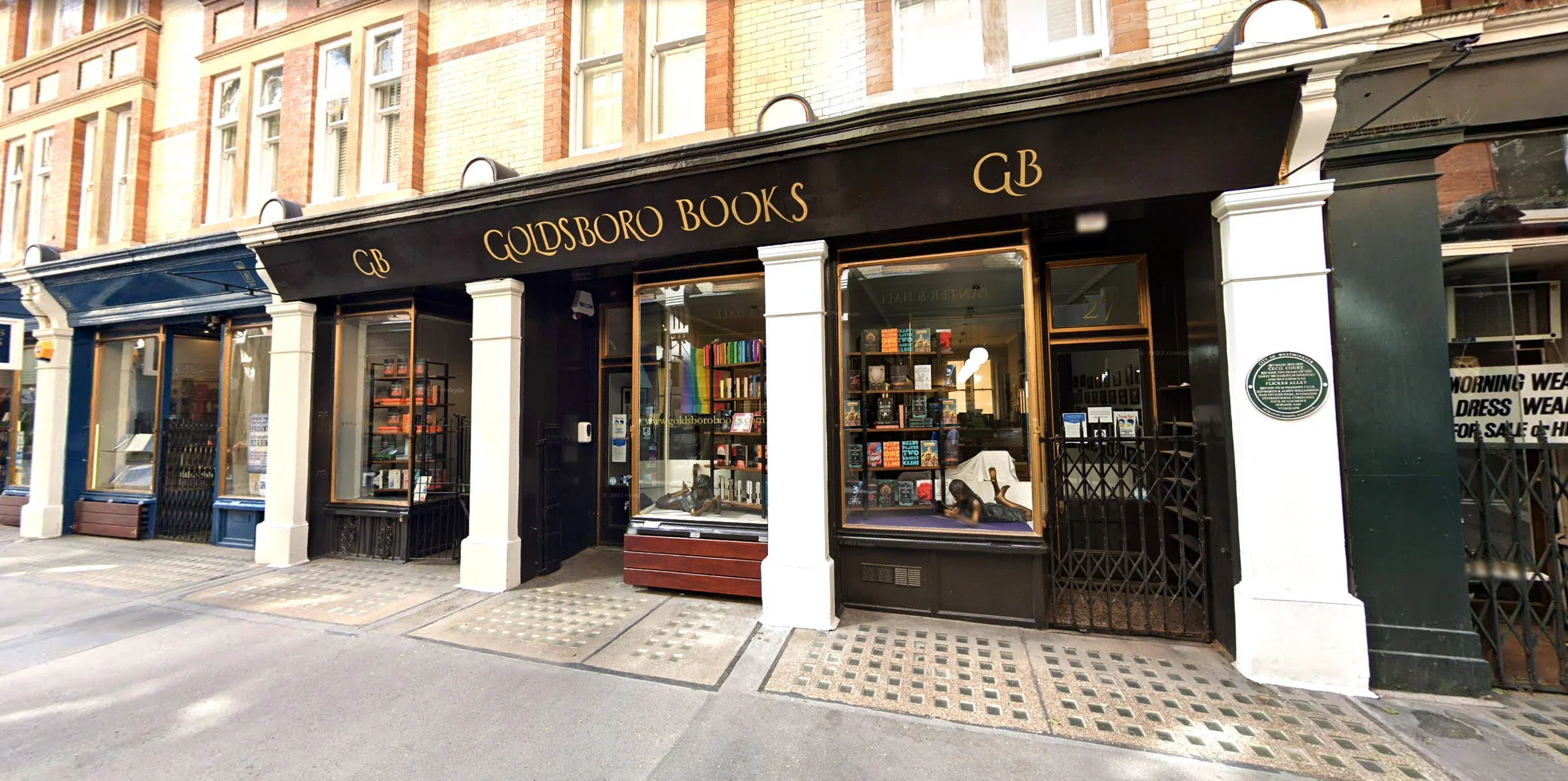 Exterior of Goldsboro Books storefront with black awning, gold lettering, and large display windows showing books inside, located on a city street.