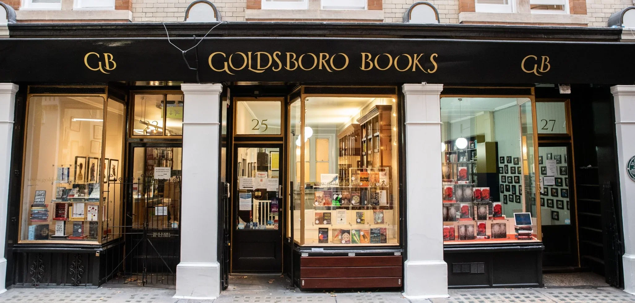 Exterior of a bookstore called Goldsboro Books with a black awning, gold lettering, and large display windows showcasing books inside and outside.