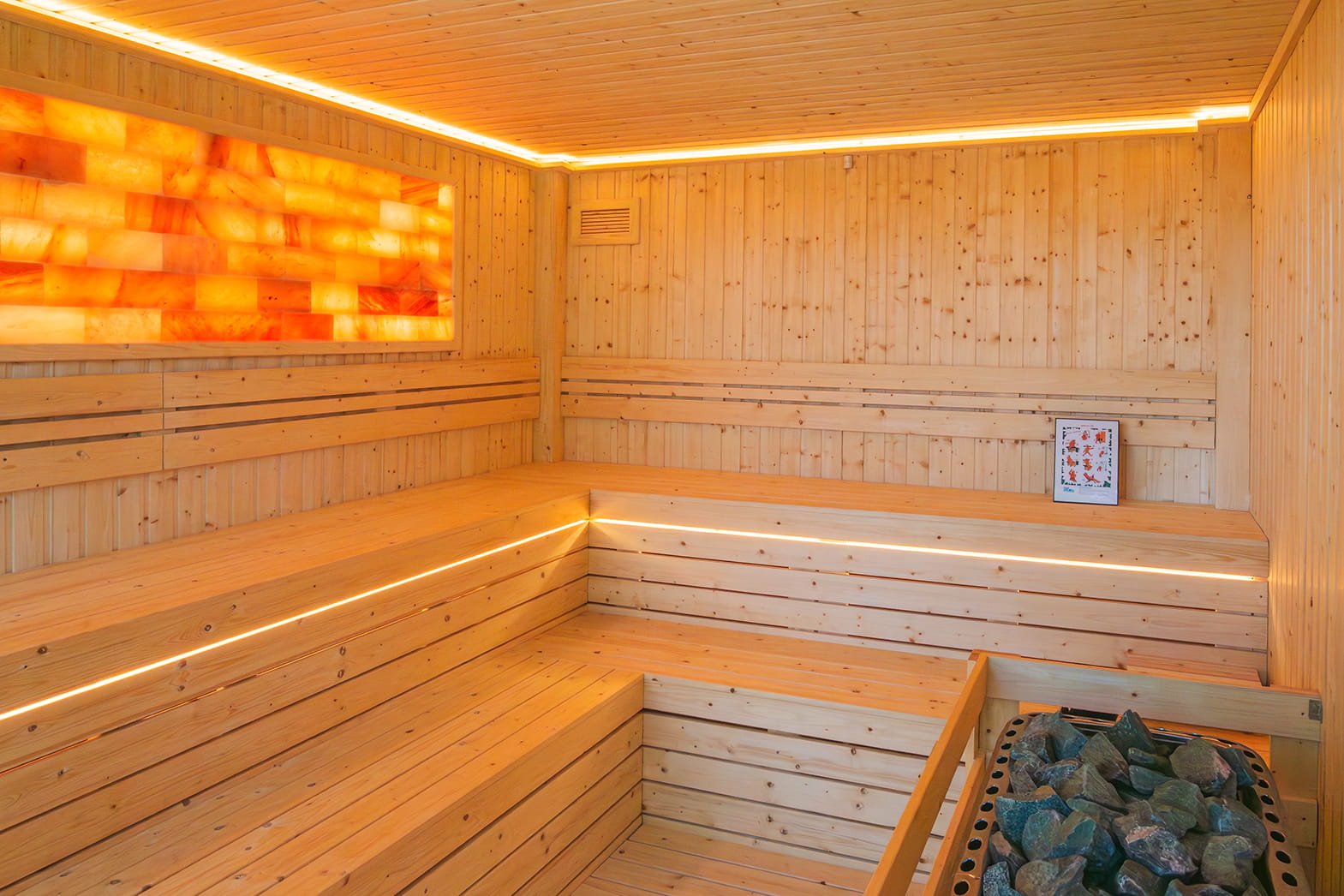 Inside a wooden sauna with benches and a salt rock heater.