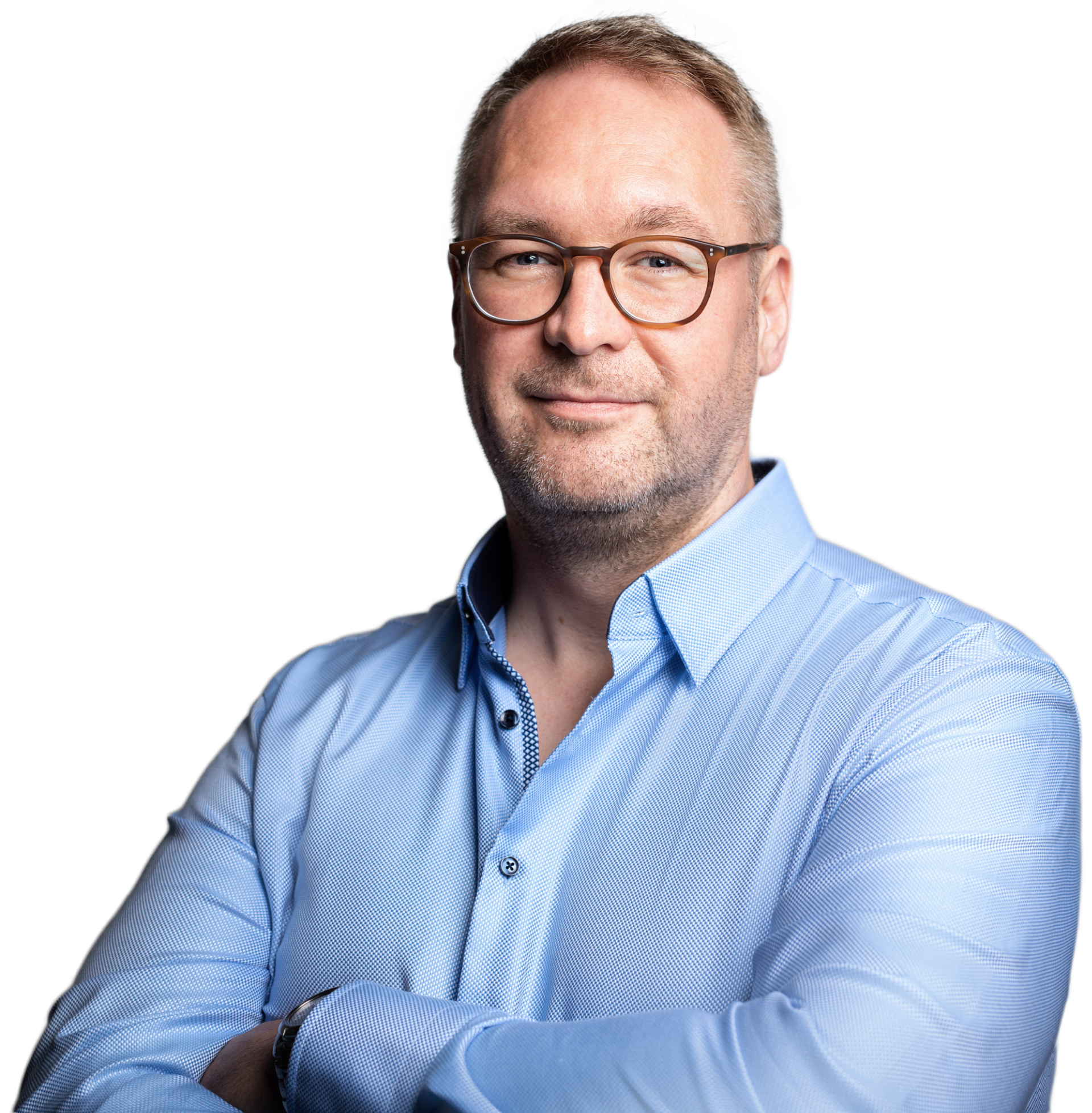 Porträt eines Mannes mit Brille, kurzer Blondhaar, im blauen Hemd, lächelnd, vor schwarzem Hintergrund.