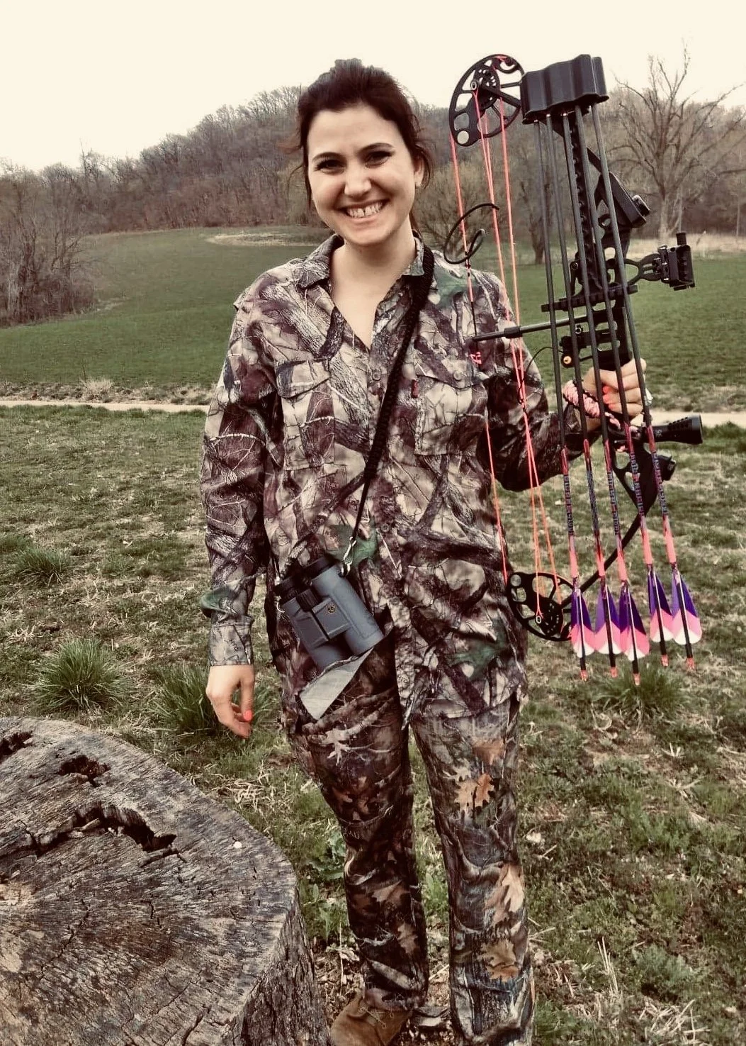 Photo of shop owner wearing camouflage and holding archery equipment