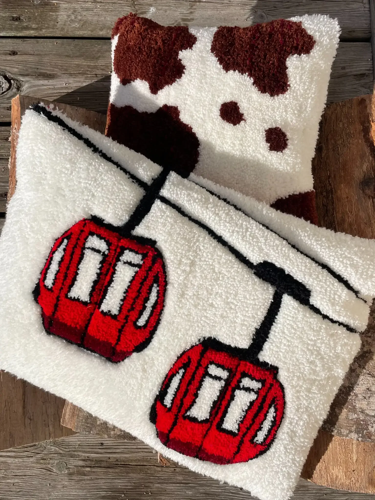Coussin tufté fait main avec motif télécabines rouges sur fond blanc, inspiration stations de ski et décoration montagne.
