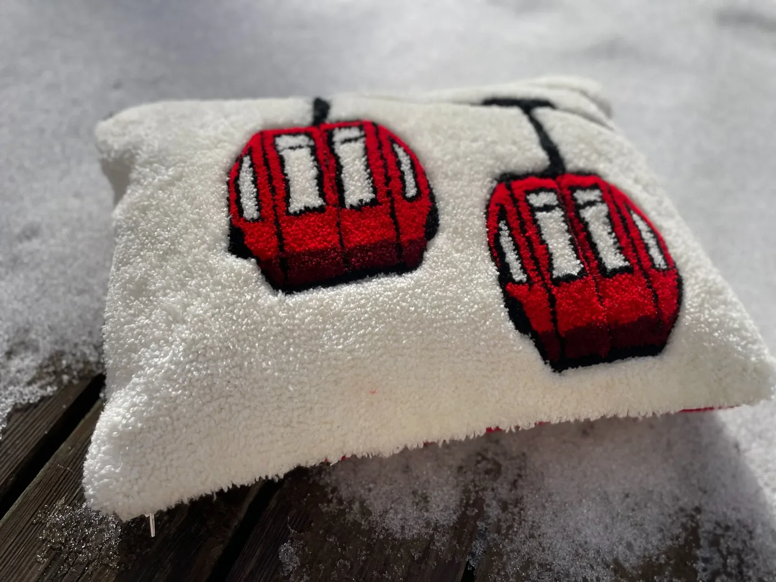 Coussin tufté artisanal représentant des télécabines rouges de montagne, création textile faite main en Haute-Savoie.