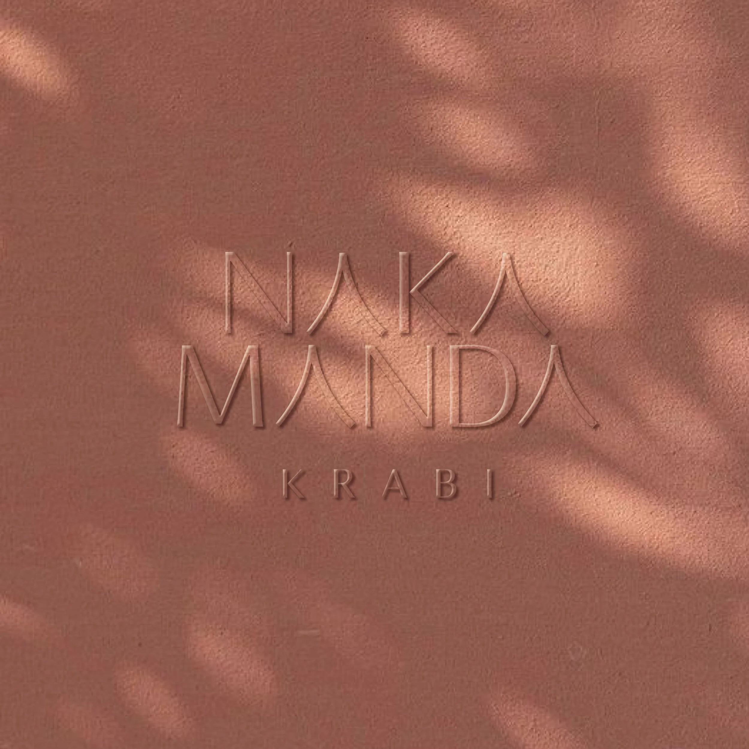 Text on a textured surface reads 'Naka Manda, Krabi' with shadows cast on the background.