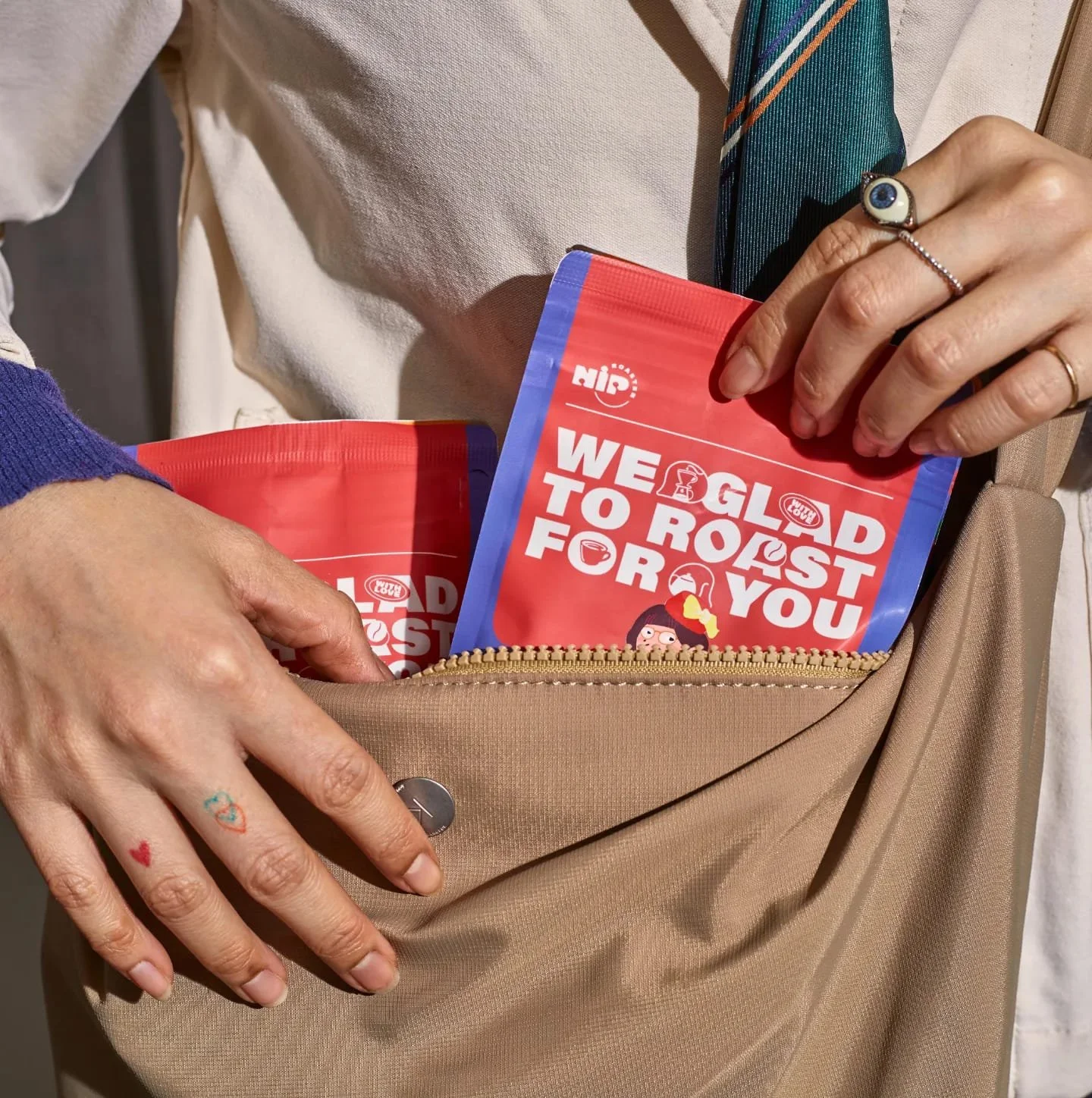 Person placing red packets with white text and cartoon character design into a beige purse with a zipper.