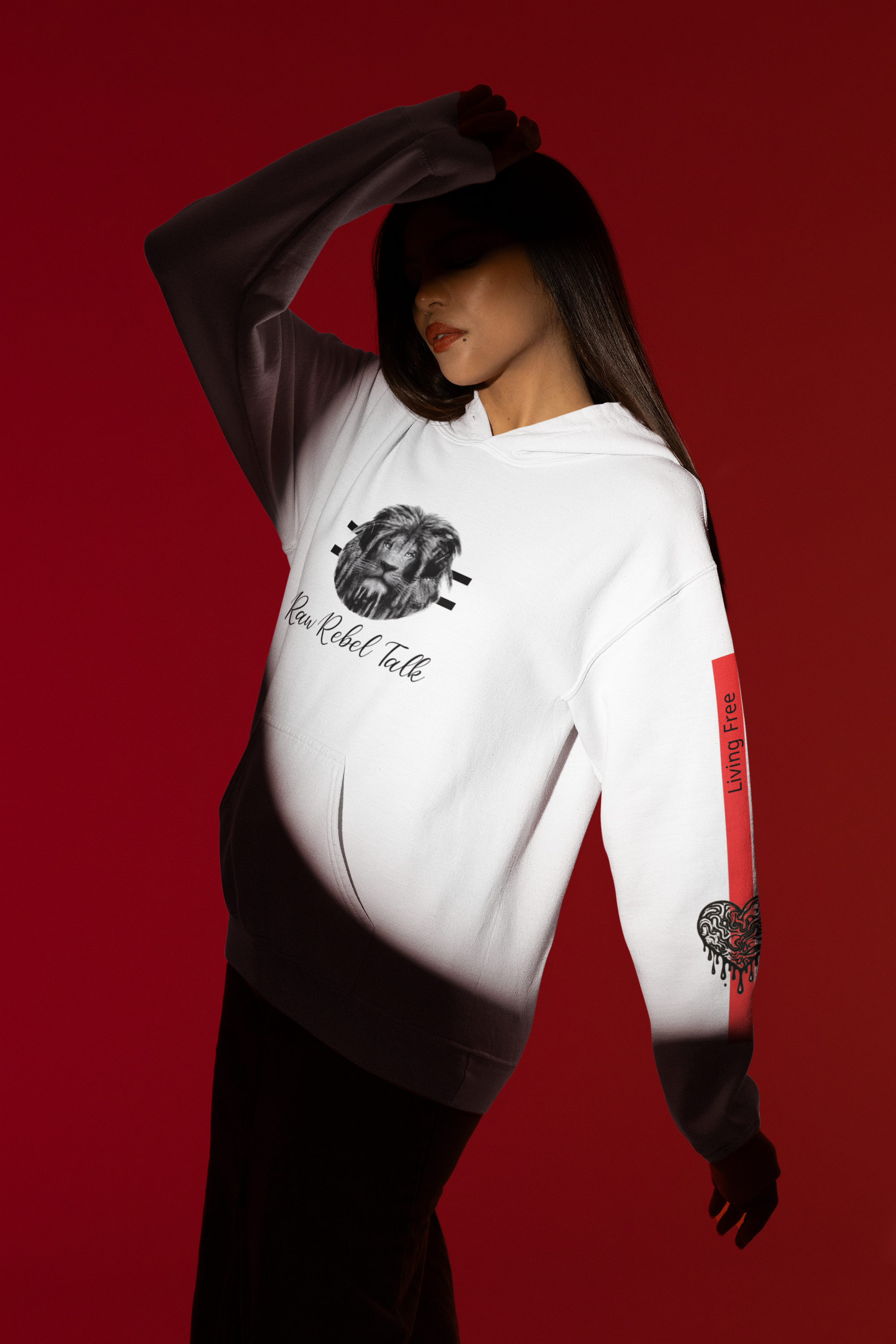 A woman wearing a white hoodie with a lion graphic and the text 'Raw Rebel Talk,' with red and black graphic on the sleeve, in front of a red background.