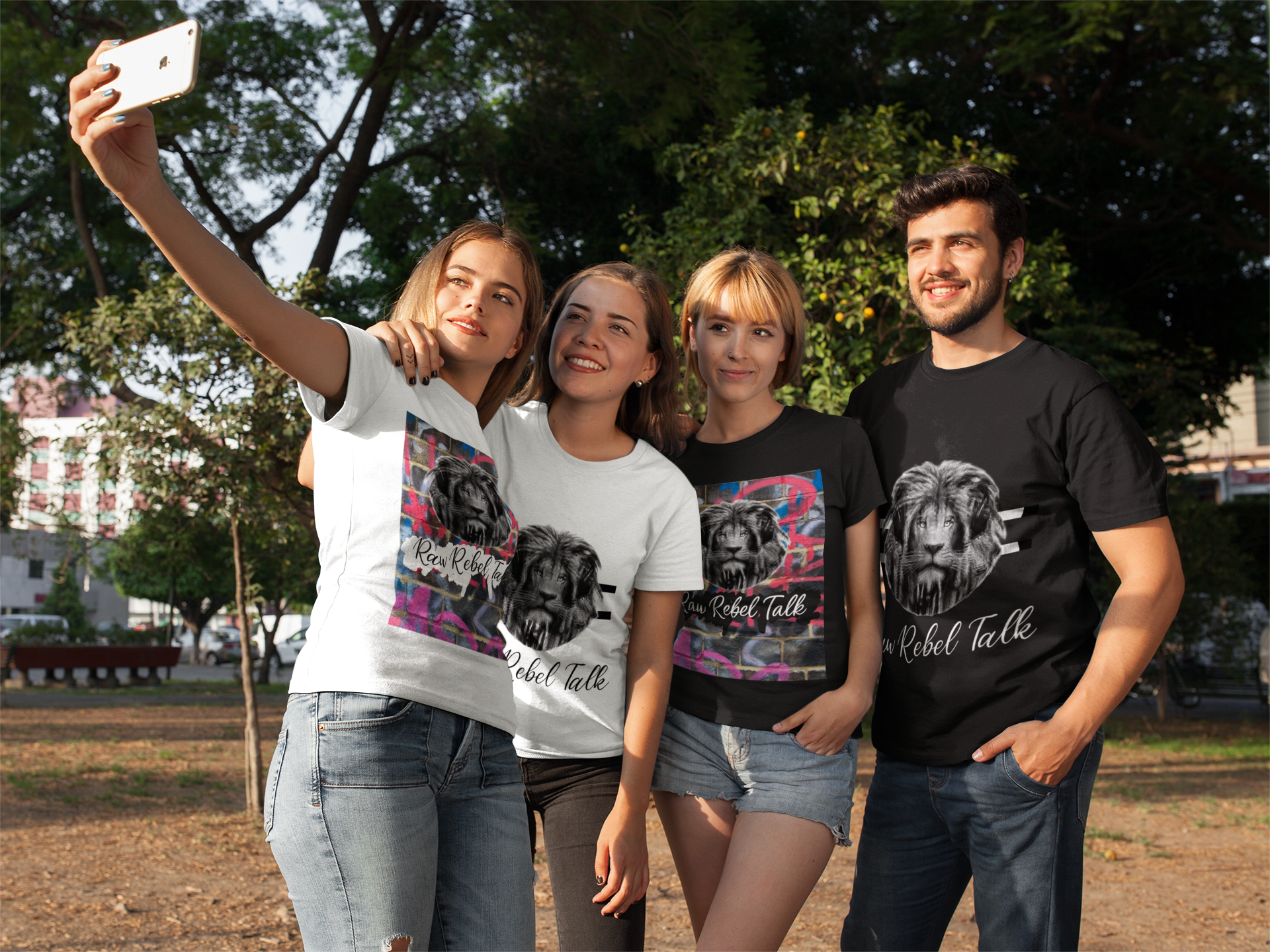 Four young adults taking a selfie together outdoors in a park on a sunny day. They are wearing t-shirts with lion artwork and the text "Raw Rebel Talk."