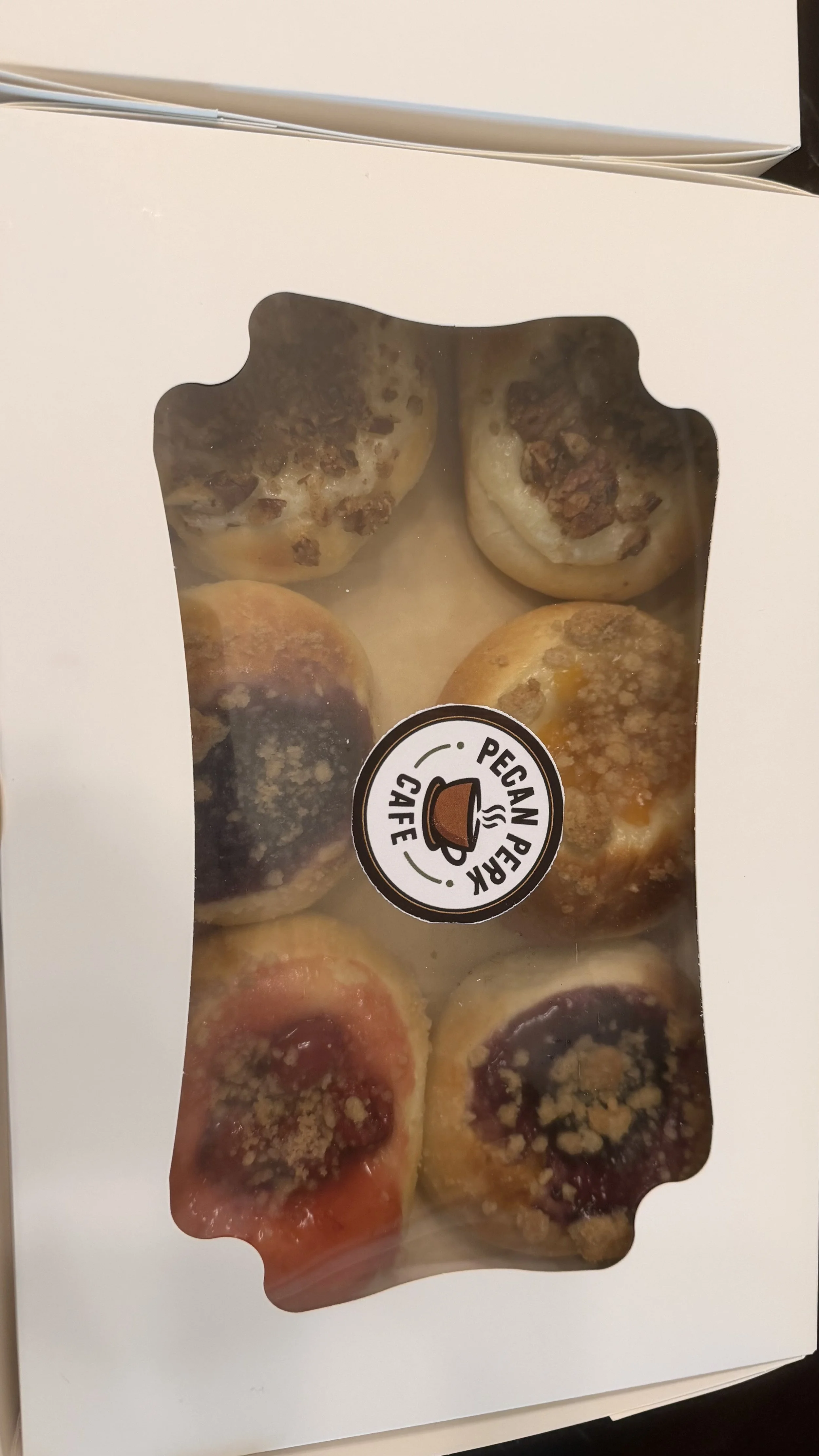 Box of six vegan pecan pie muffins with crumb topping inside a white bakery box.