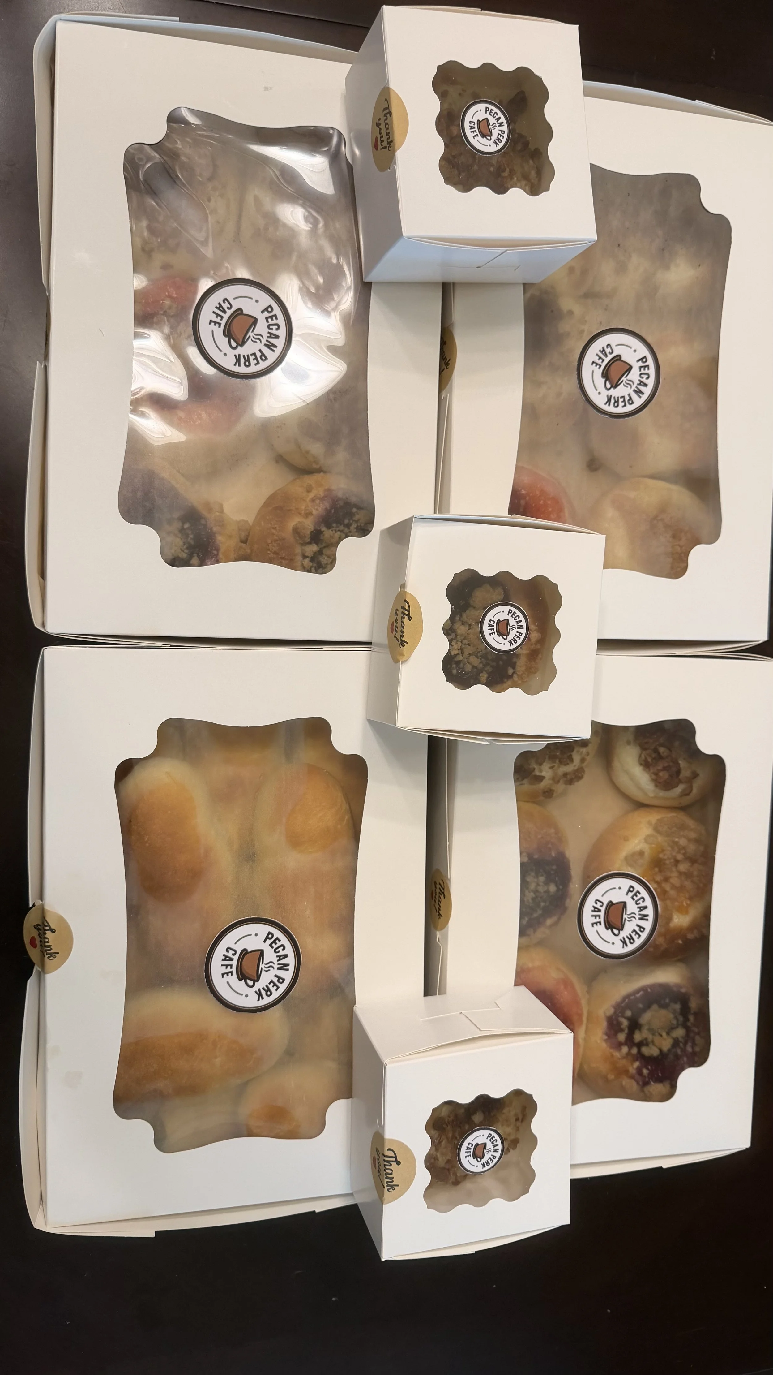 Four boxes and two smaller boxes of pastries with transparent windows showing baked goods, labeled 'Pecan Bear Café'.