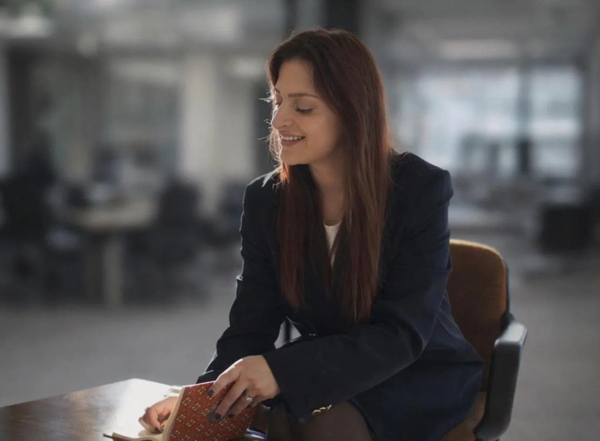 Une femme assise à une table en train de feuilleter un carnet dans un bureau moderne