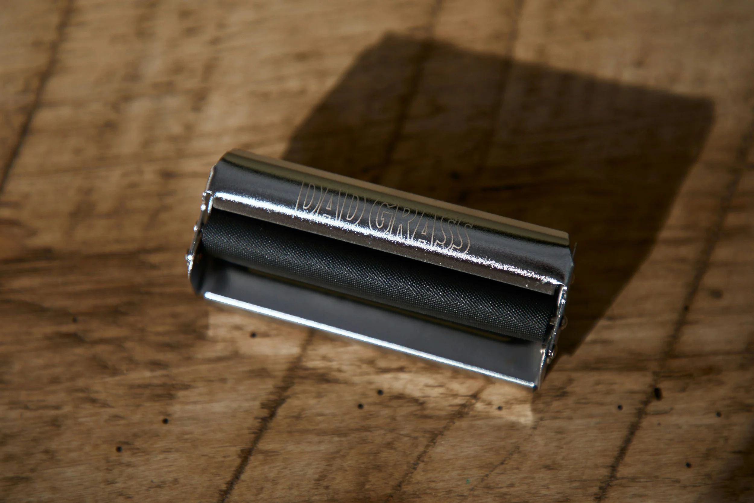 Un rasoir en métal sur une surface en bois, avec une ombre projetée visible à côté.