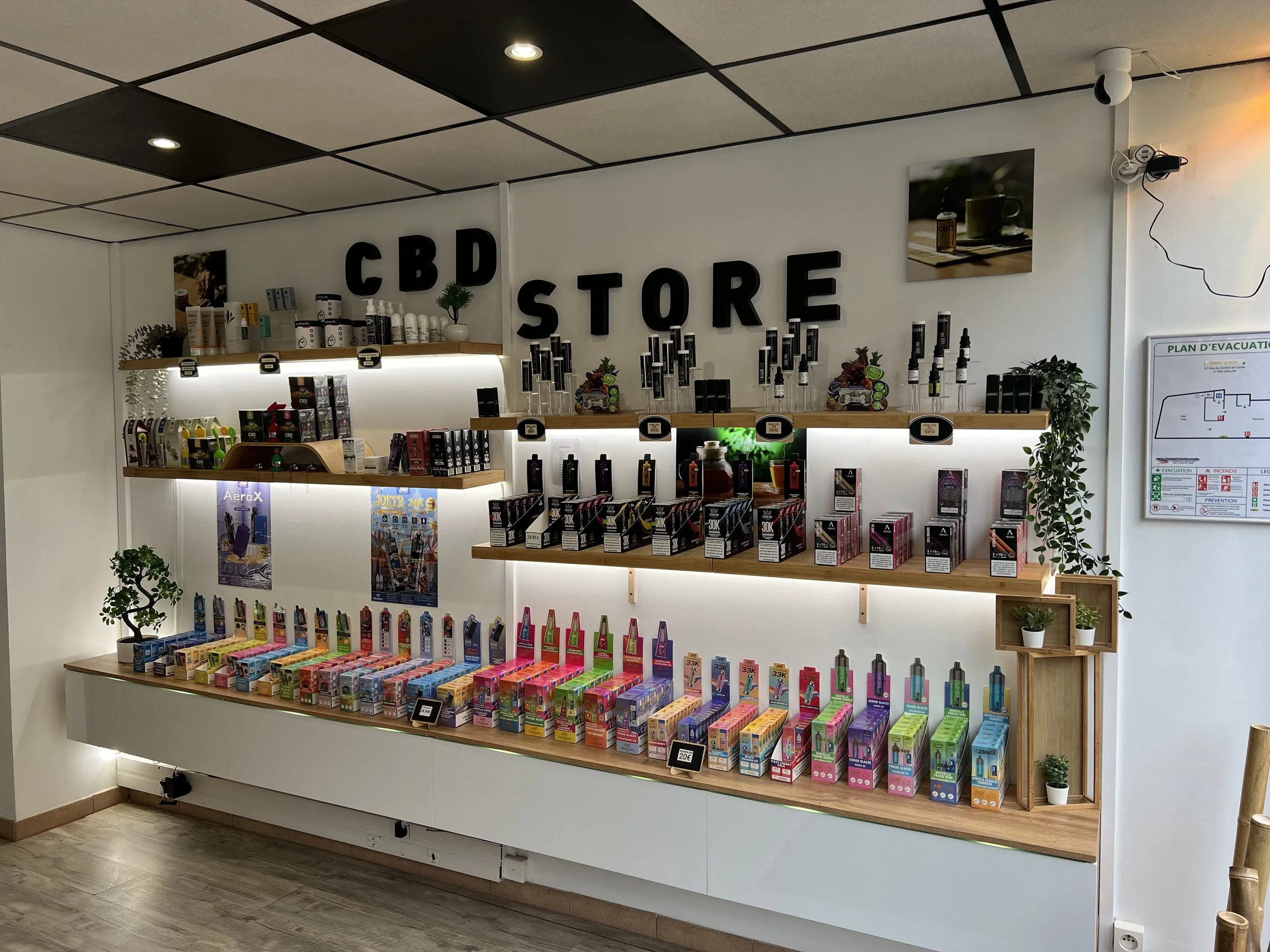 Une étagère dans un magasin CBD avec des produits variés, affichés en rangées, sous un panneau noir avec la mention 'CBD STORE'.