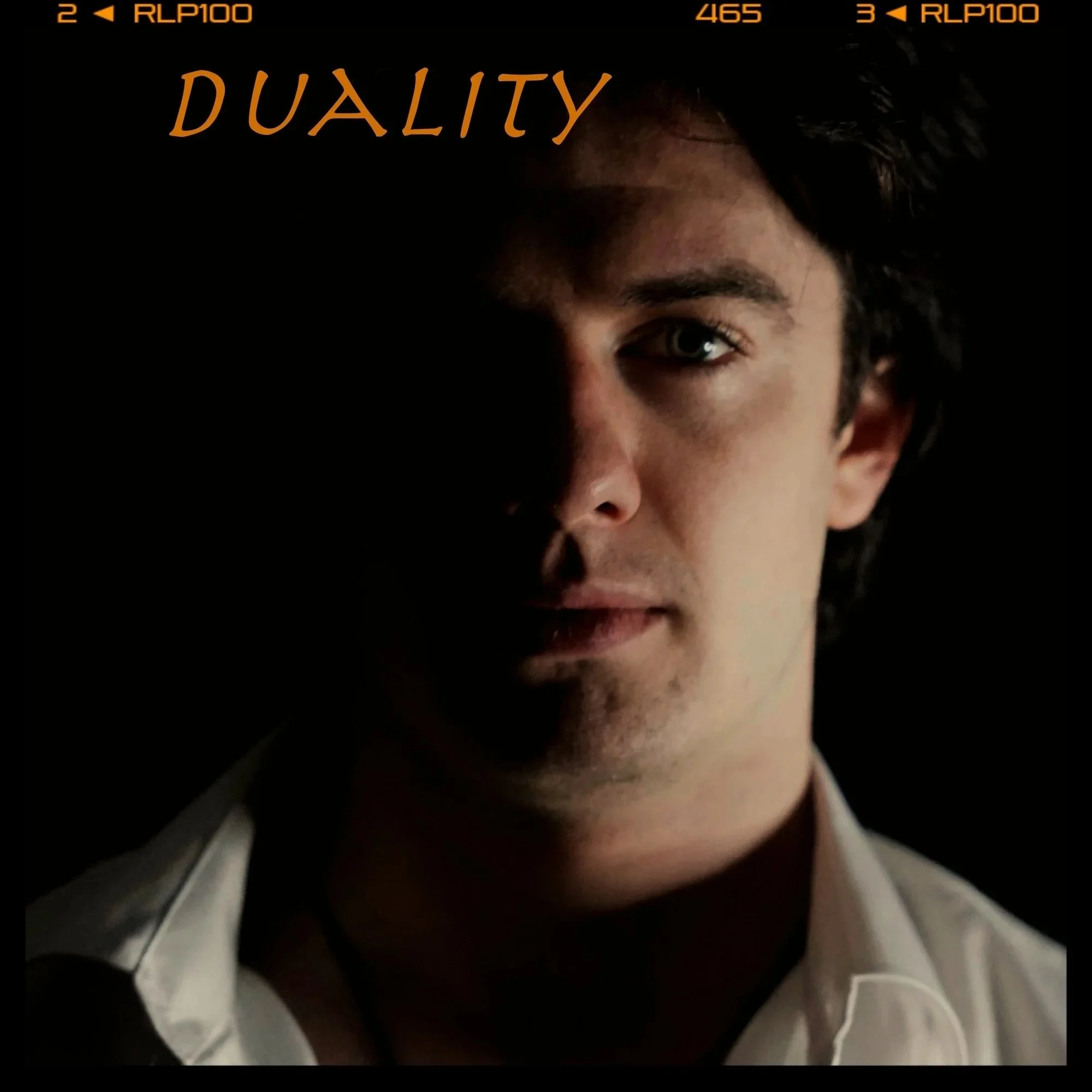 A man with half of his face in shadow, wearing a collared shirt, with the word 'DUALITY' in orange text above his head.