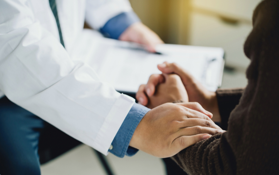 A doctor holding a patient's hands during a consultation.