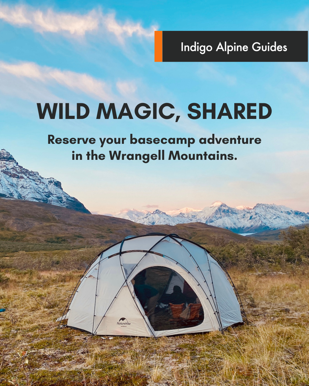 A camping tent set up in a grassy field with mountains in the background under a partly cloudy sky.