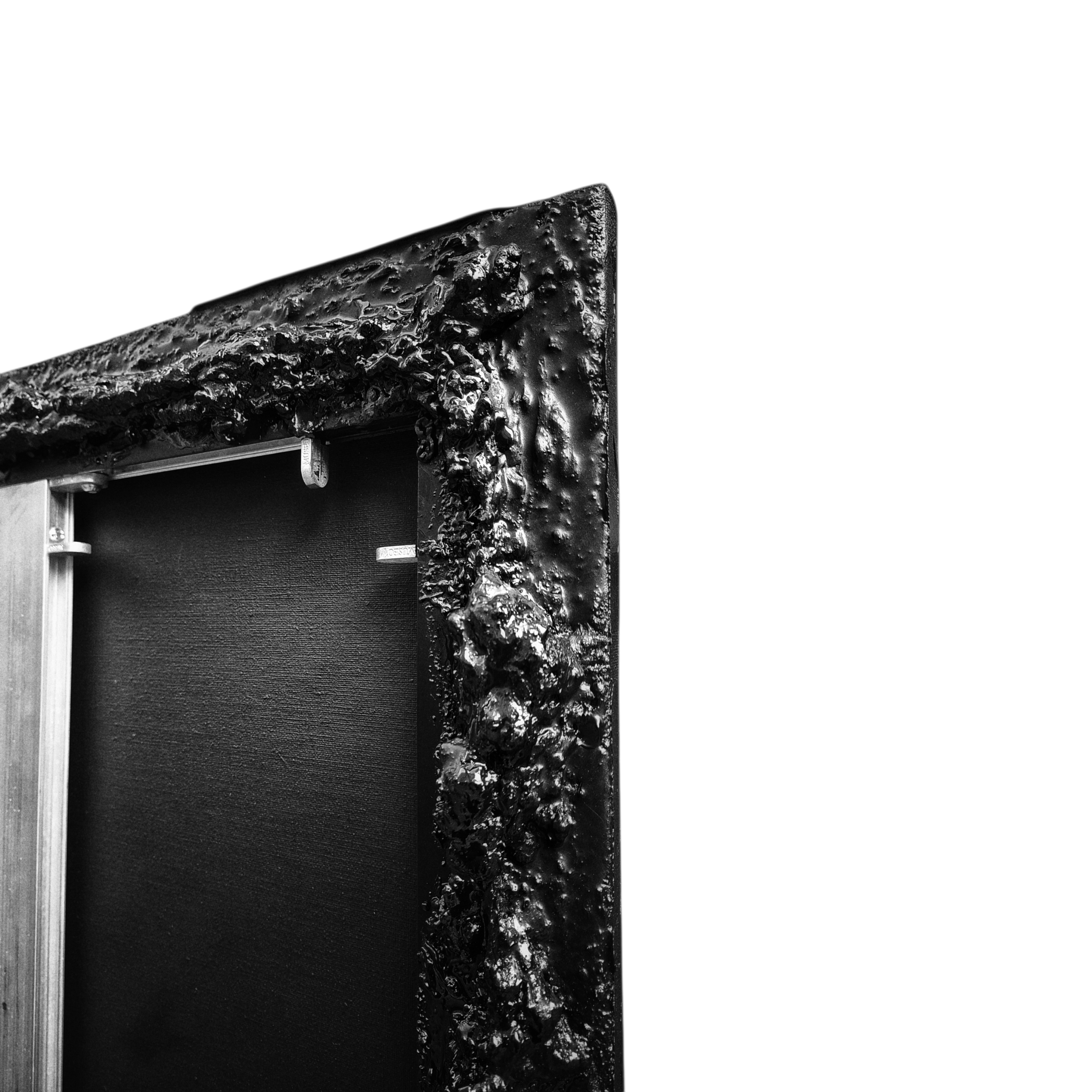 Coin supérieur gauche d'un tableau avec cadre noir, avec un cadre en bois et une toile sombre, vue partielle. La photo est en noir et blanc.