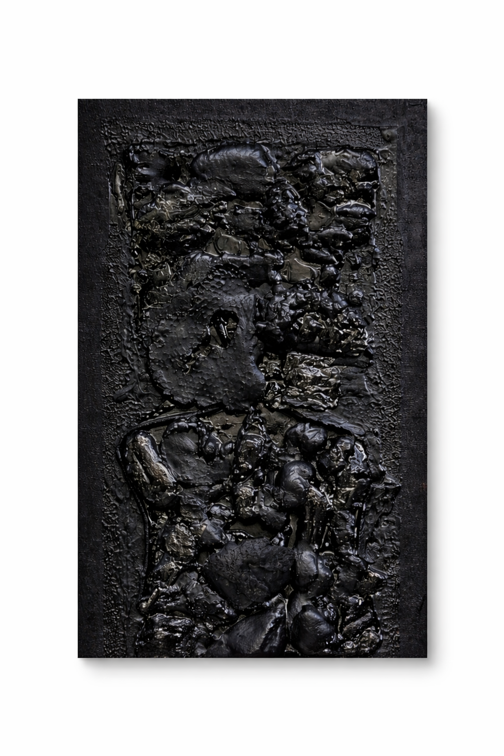 Une œuvre d'art en relief en noir présentant une composition abstraite avec des formes rocheuses et texturées.