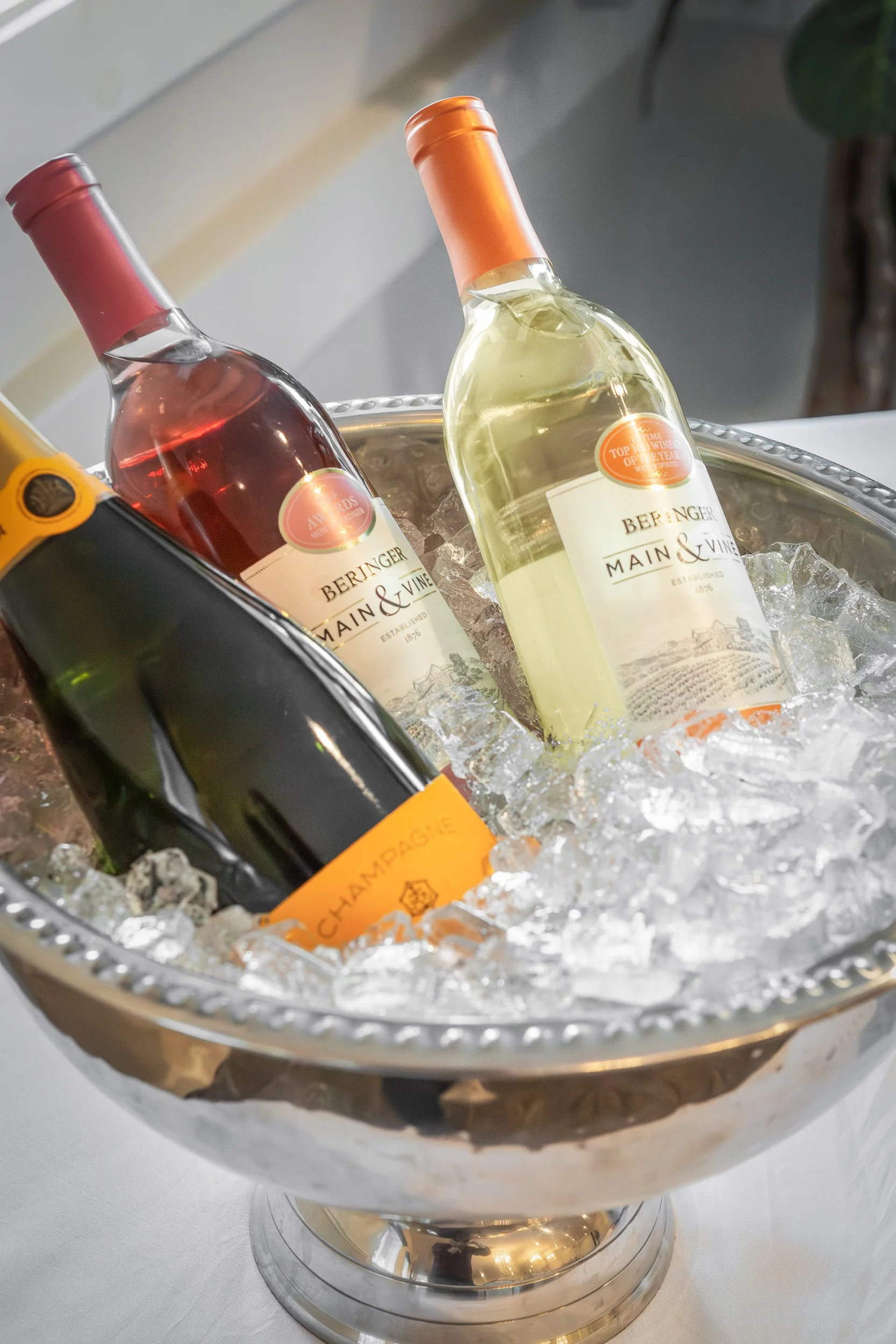 Bottles of wine and champagne chilling in a silver ice basin filled with ice.