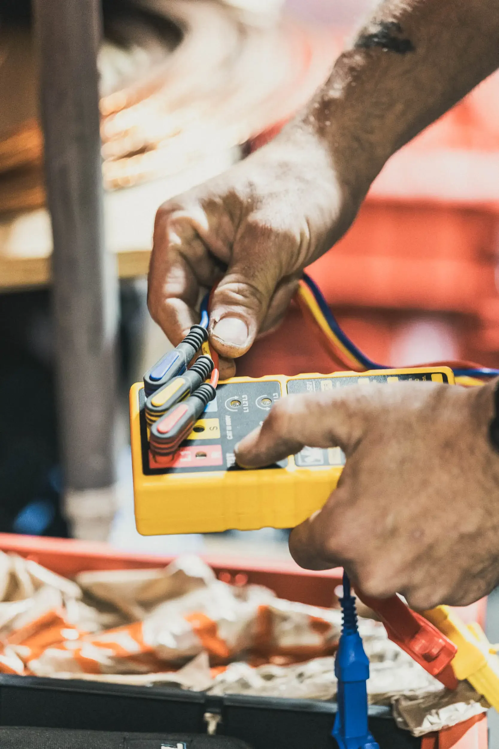 Close-up of a person connecting electrical wires to a device, with fried food in the background.