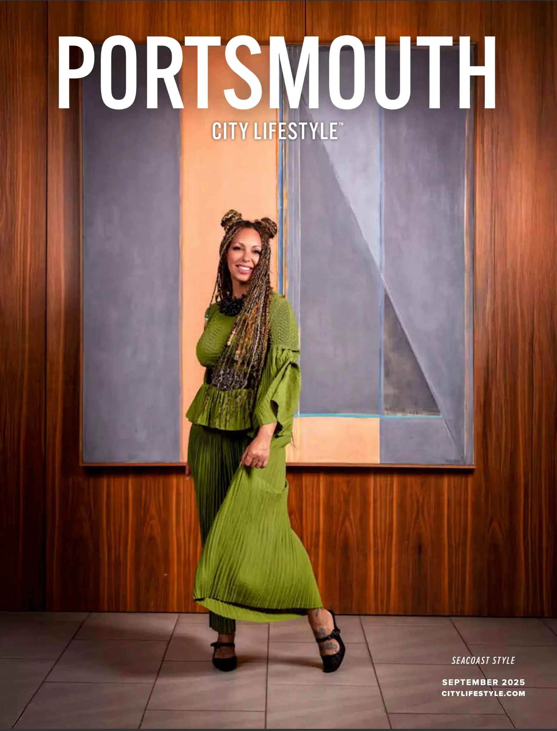 A woman with long multicolored braids, wearing a ruffled green dress and black heels, stands in front of a wooden wall with large text reading 'Portsmouth City Lifestyle', along with the logo and date 'September 2025' and the website 'citylifestyle.c