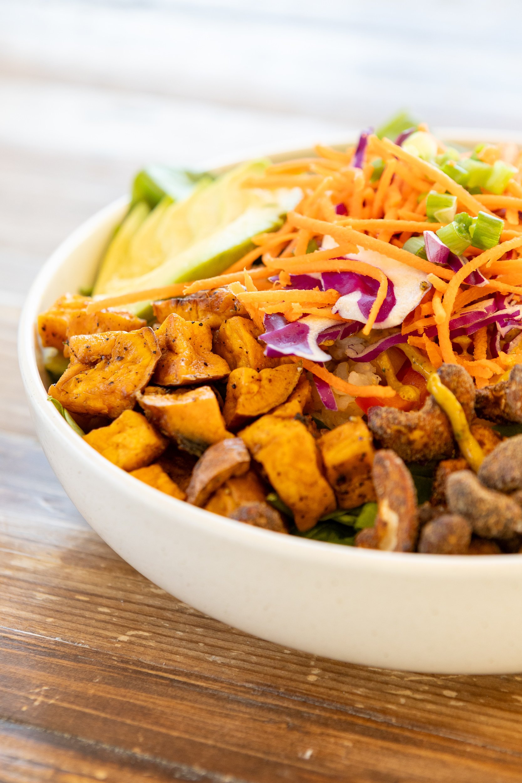 A bowl of chicken tacos with shredded cheese, diced chicken, lettuce, jalapeños, and shredded carrots on a wooden surface.