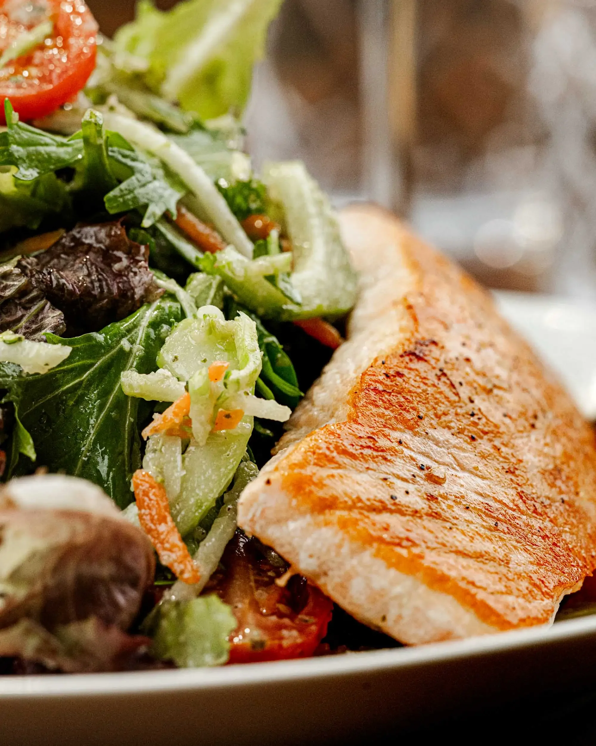 Close-up of a plate with a fresh salad and a grilled salmon fillet.