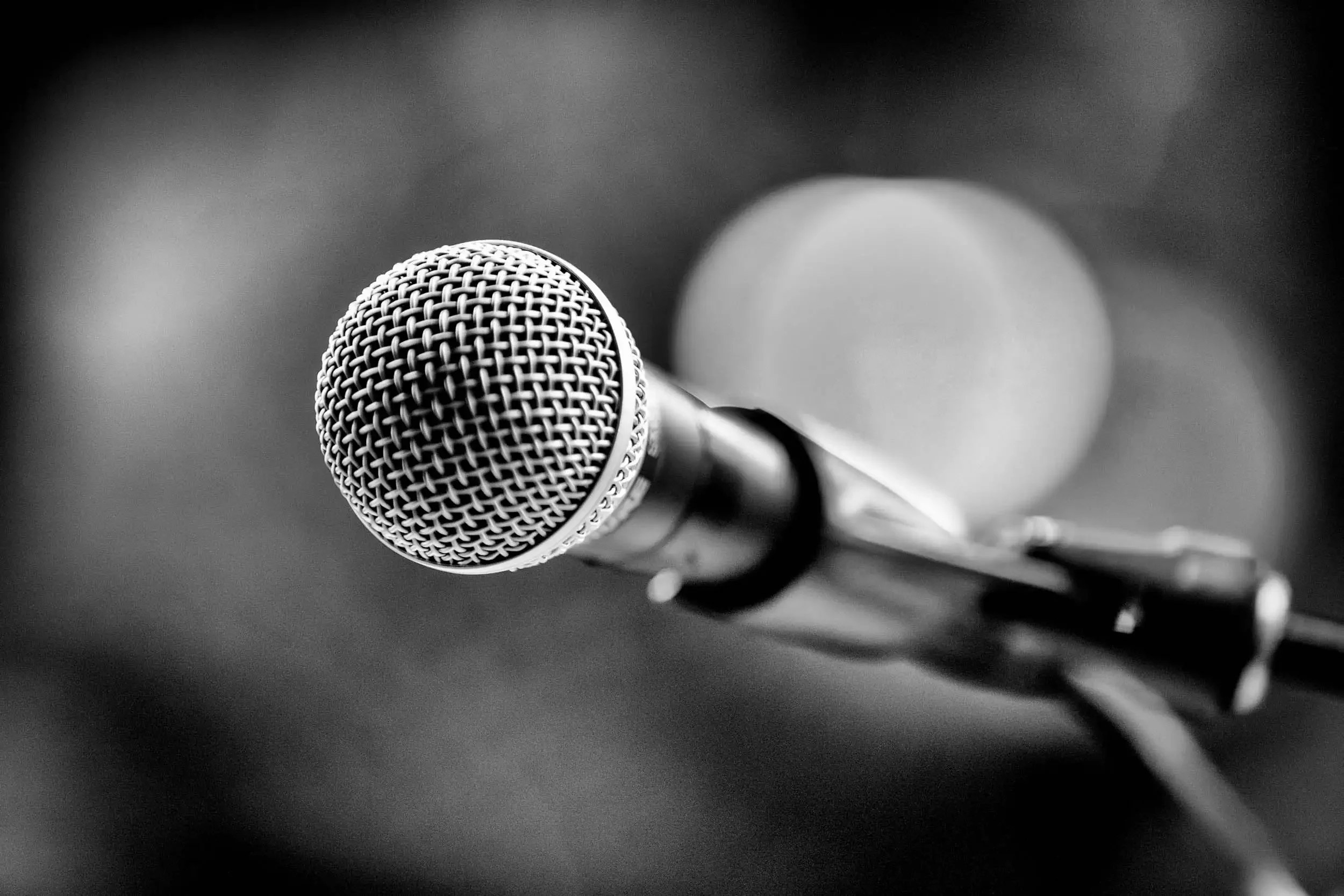 Close-up of a microphone on a stand, with a blurred background.