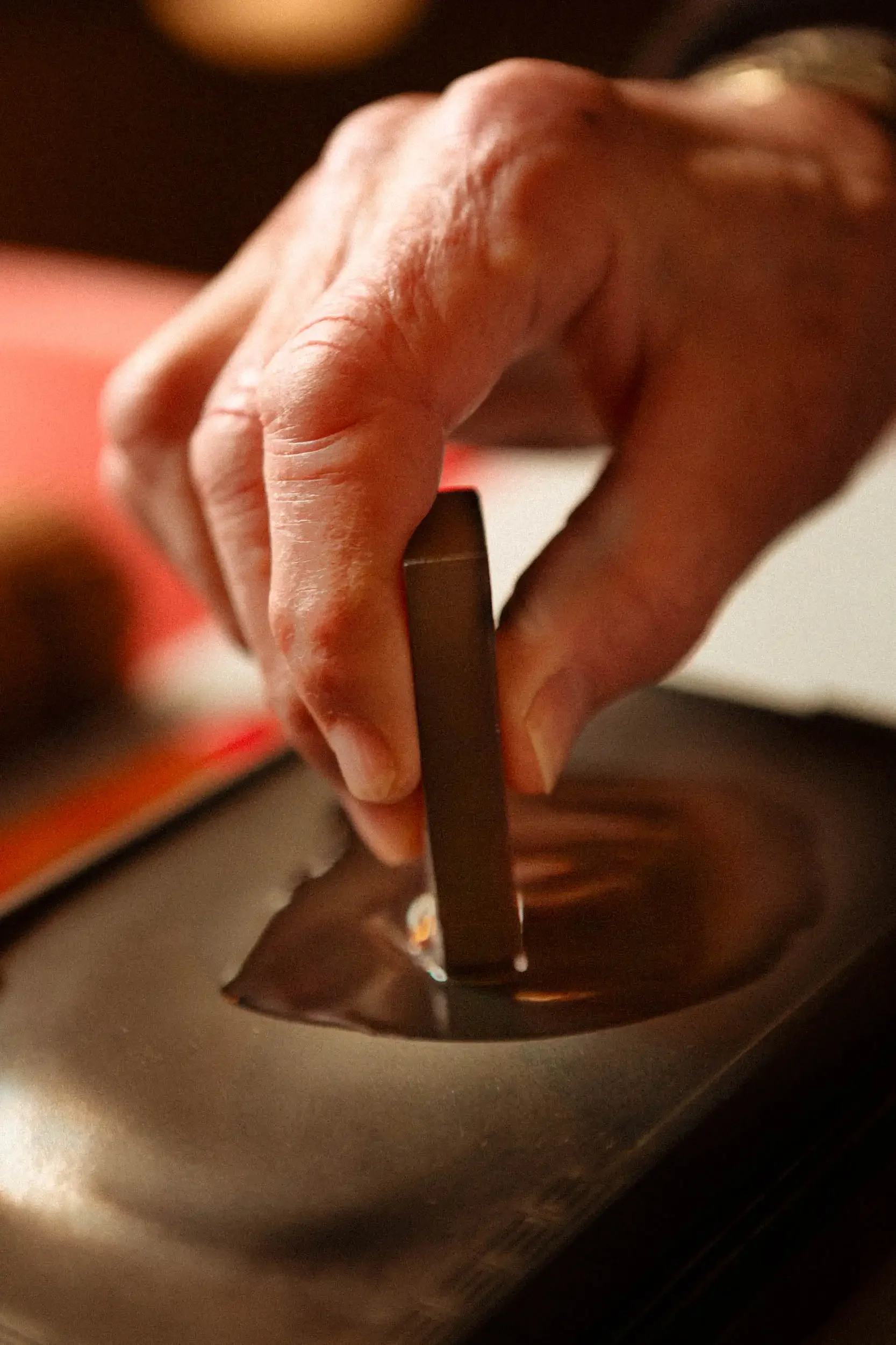 Close-up of a person's hand holding a chocolate bar over a laptop keyboard.