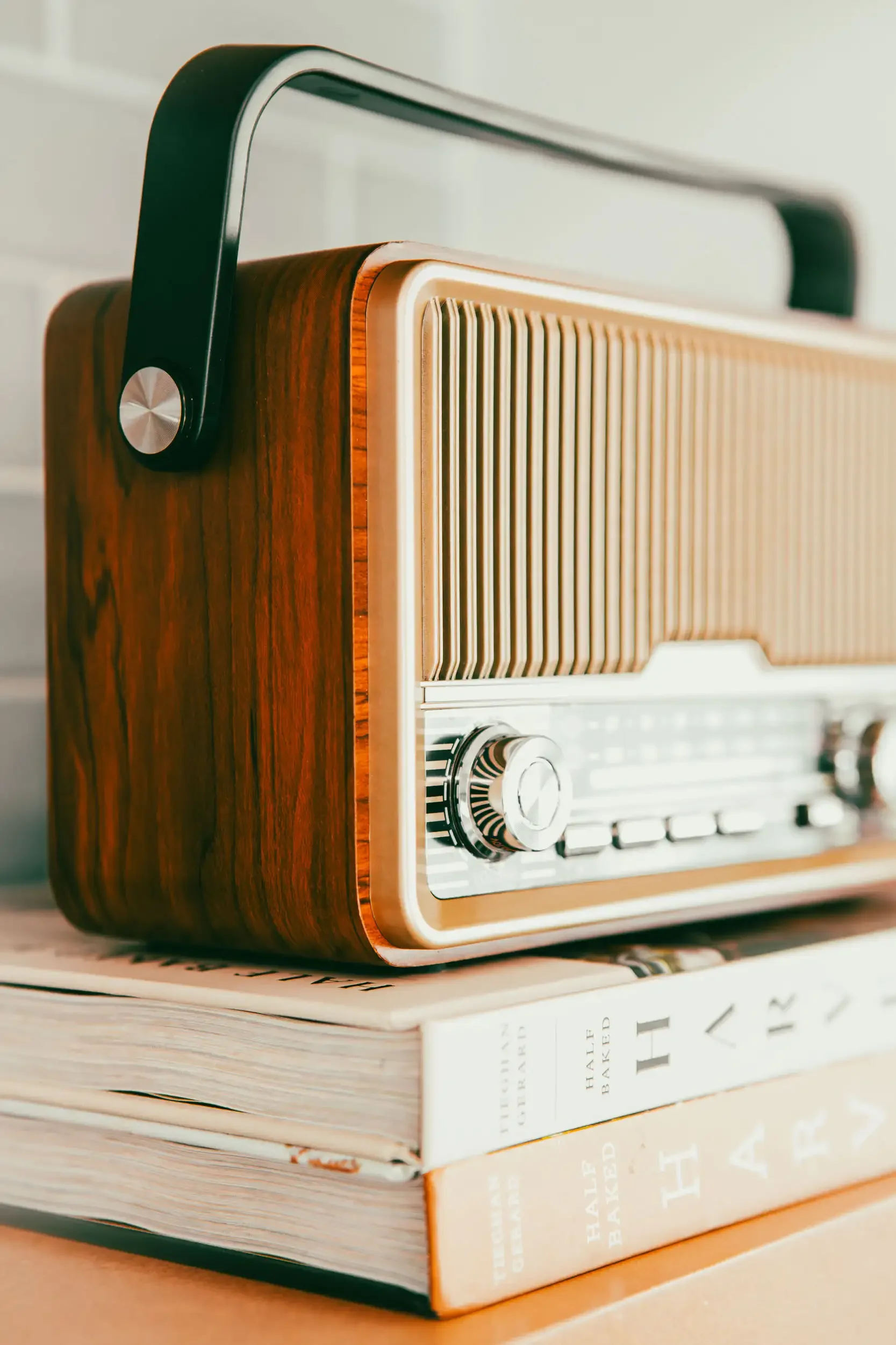 A vintage wooden radio on top of two books, with the titles 'Truman Capote' and 'The Great Baksed' visible.