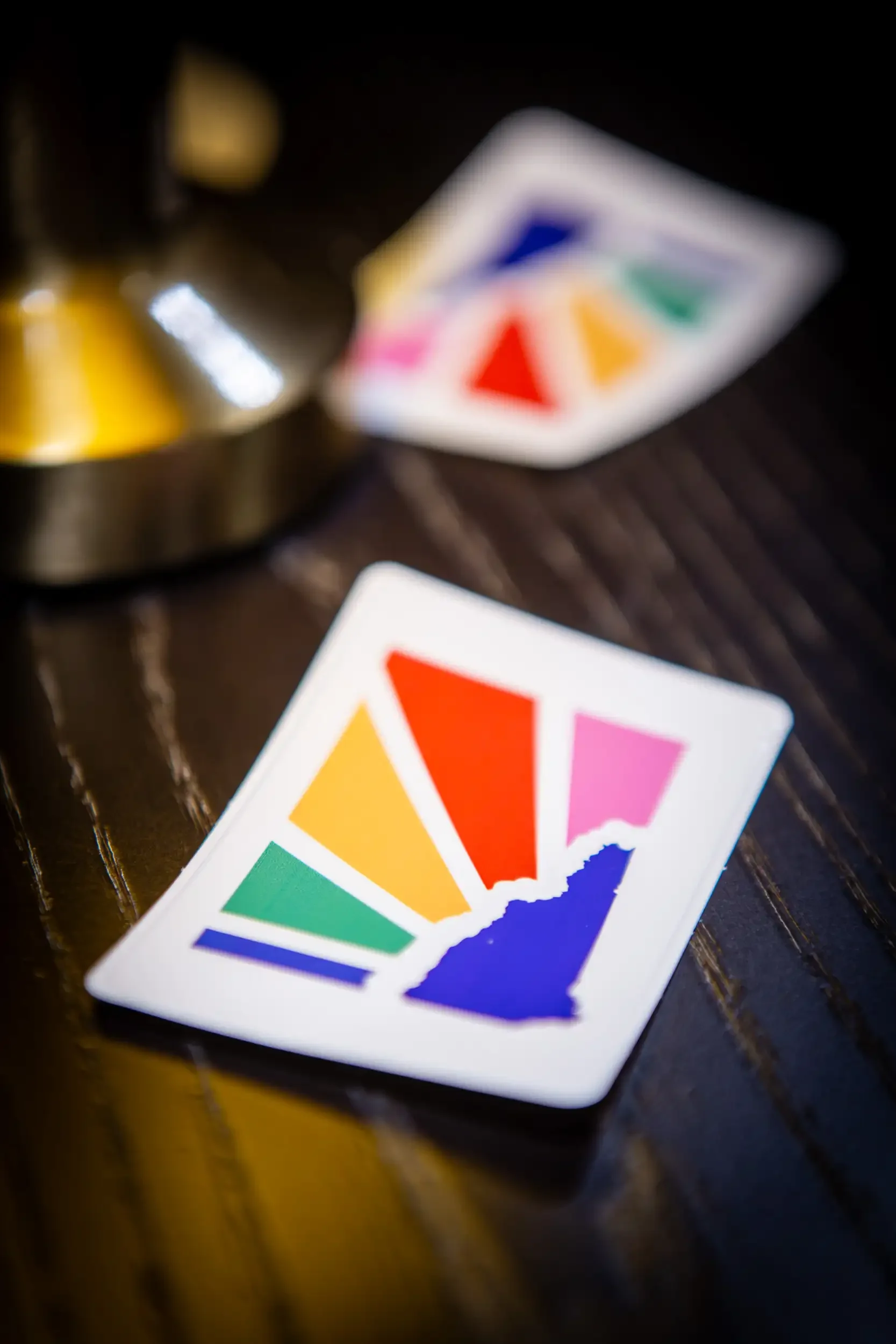 Color wheel card and a blurred metallic object on a dark wooden surface.