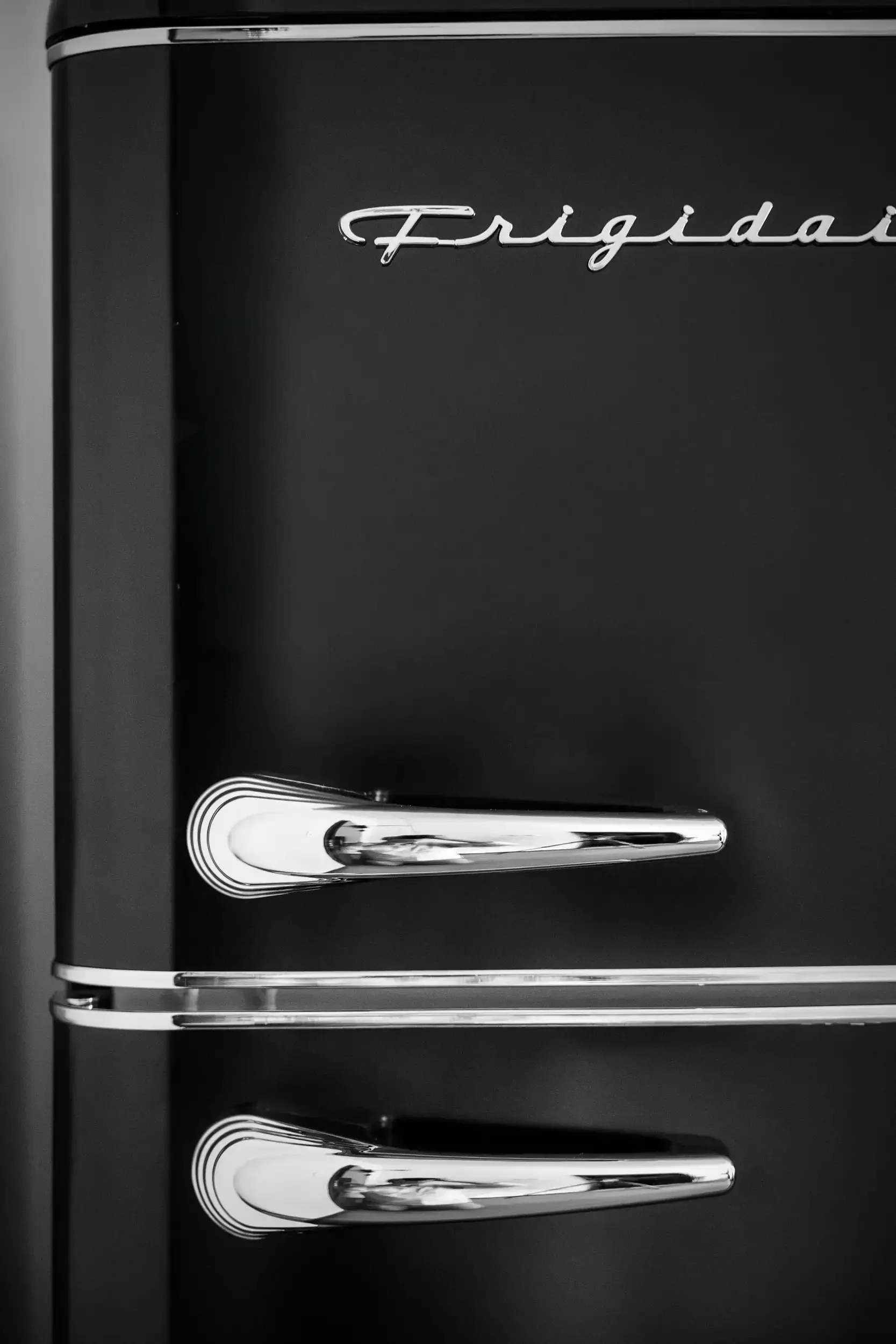 Close-up of a black refrigerator with a silver handle and the sign 'Frigidaire' in cursive on the door.