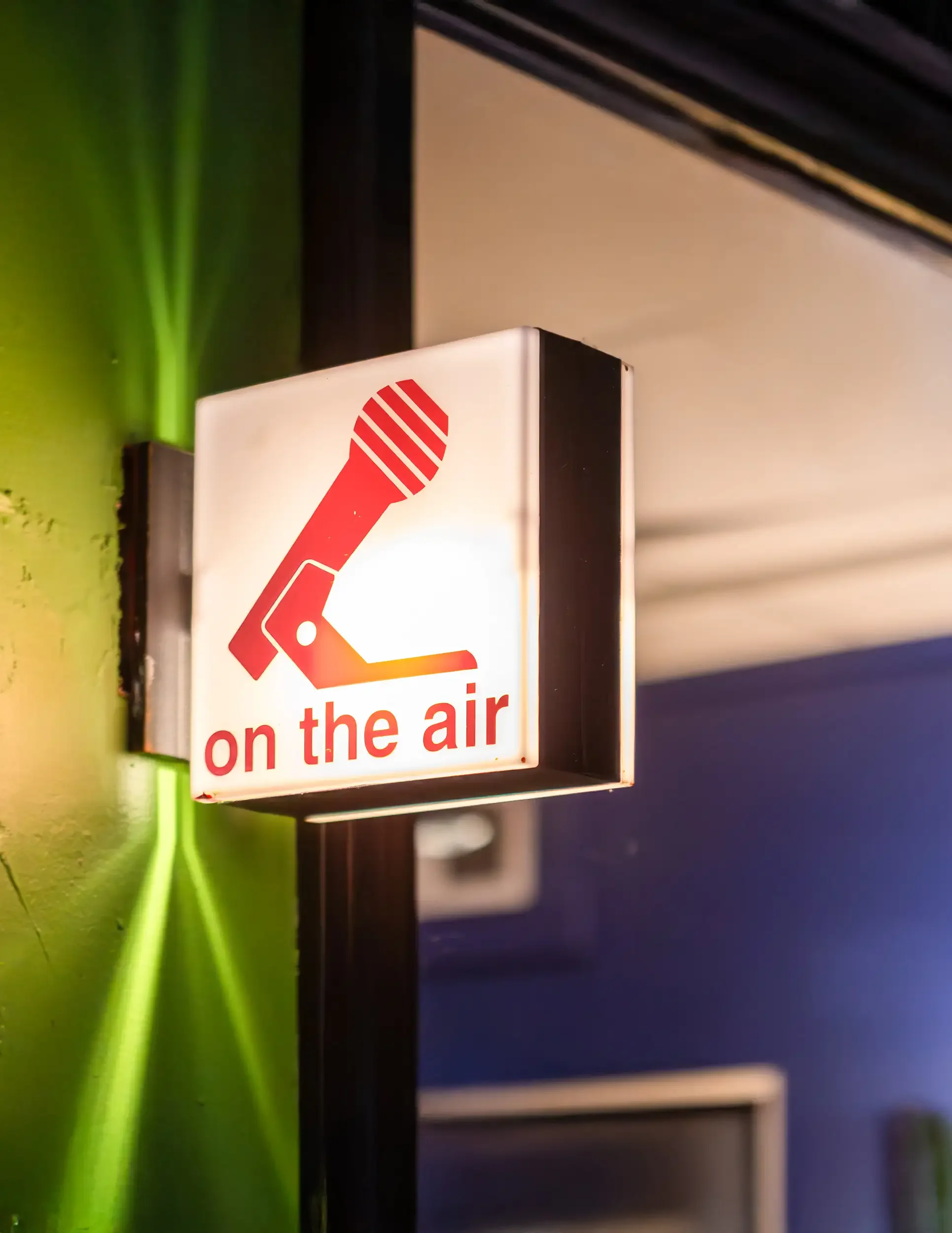 Sign with red icon of a microphone and red text that reads 'on the air'