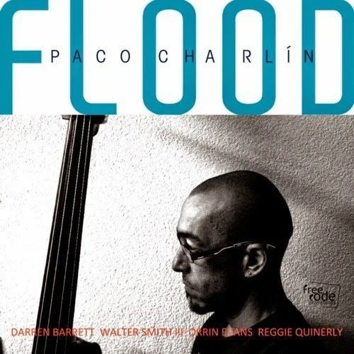 A black-and-white album cover featuring a man playing a double bass, with the title in large blue letters that spell "FLOOD" and the artist's name, Paco Charlín, above it.