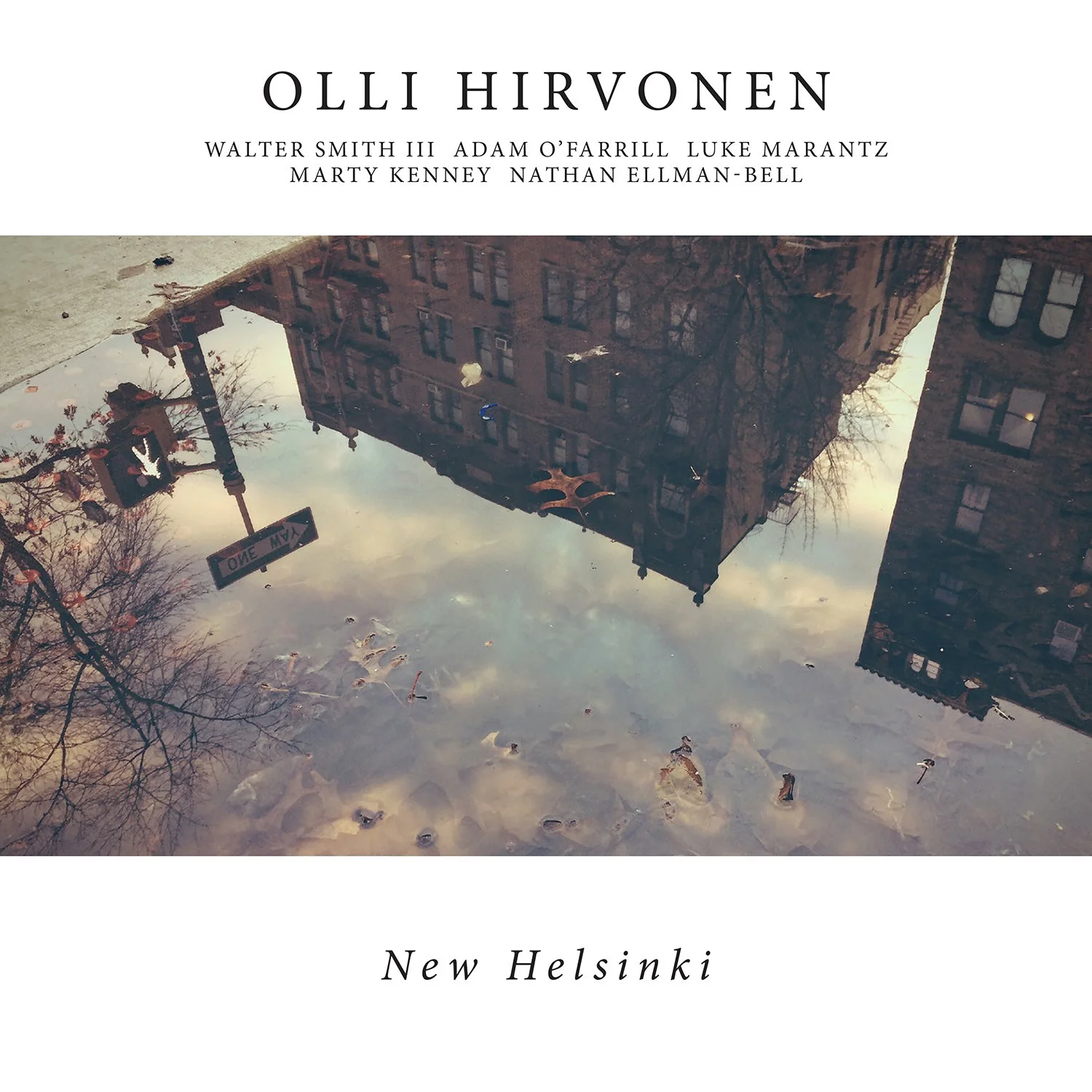 Book cover titled 'Ollli Hirvonen' with authors' names, showing a reflection of buildings, street signs, and trees in a puddle on a city street in New Helsinki.